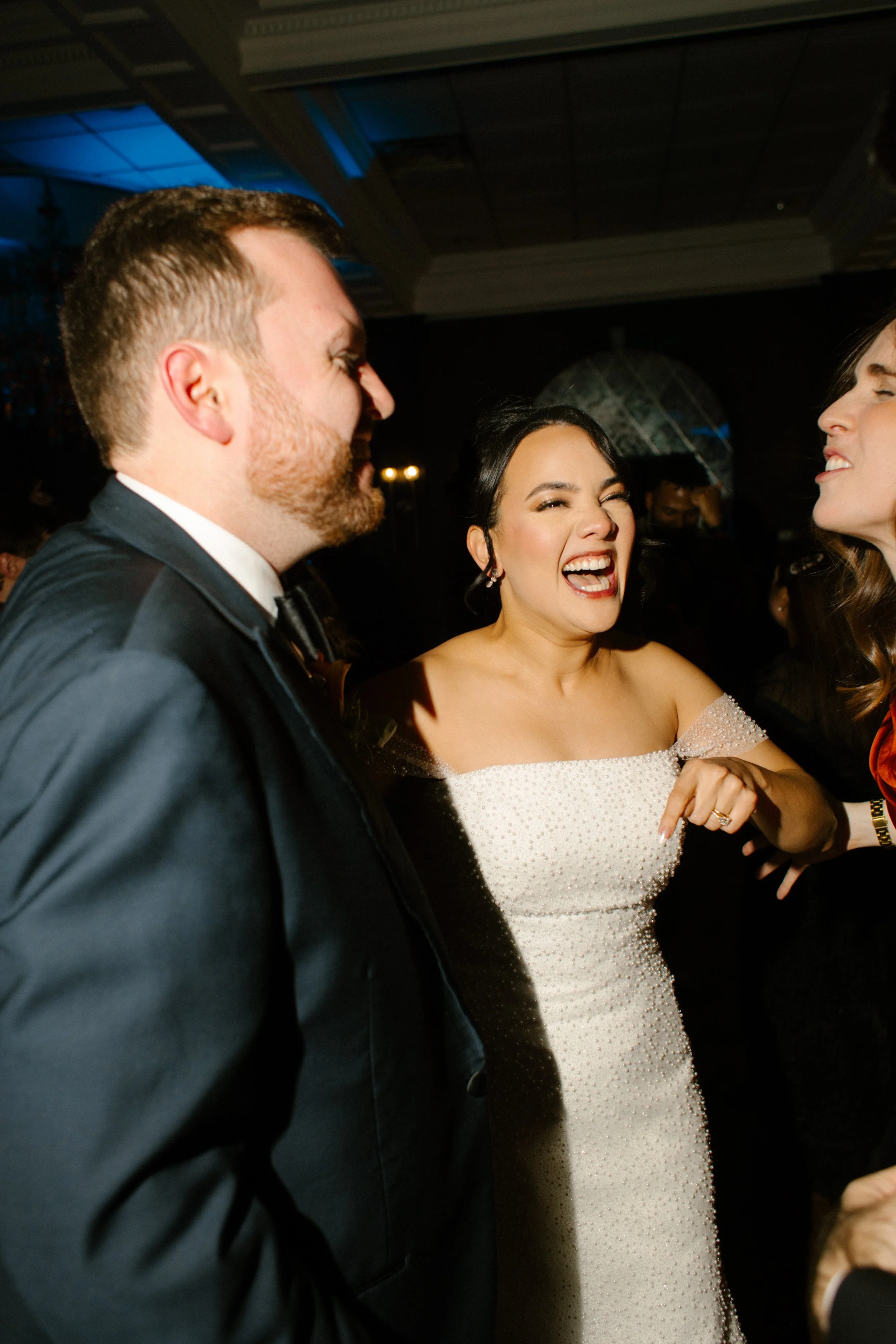 Bride and groom laughing together on the dance floor during a lively wedding reception celebration