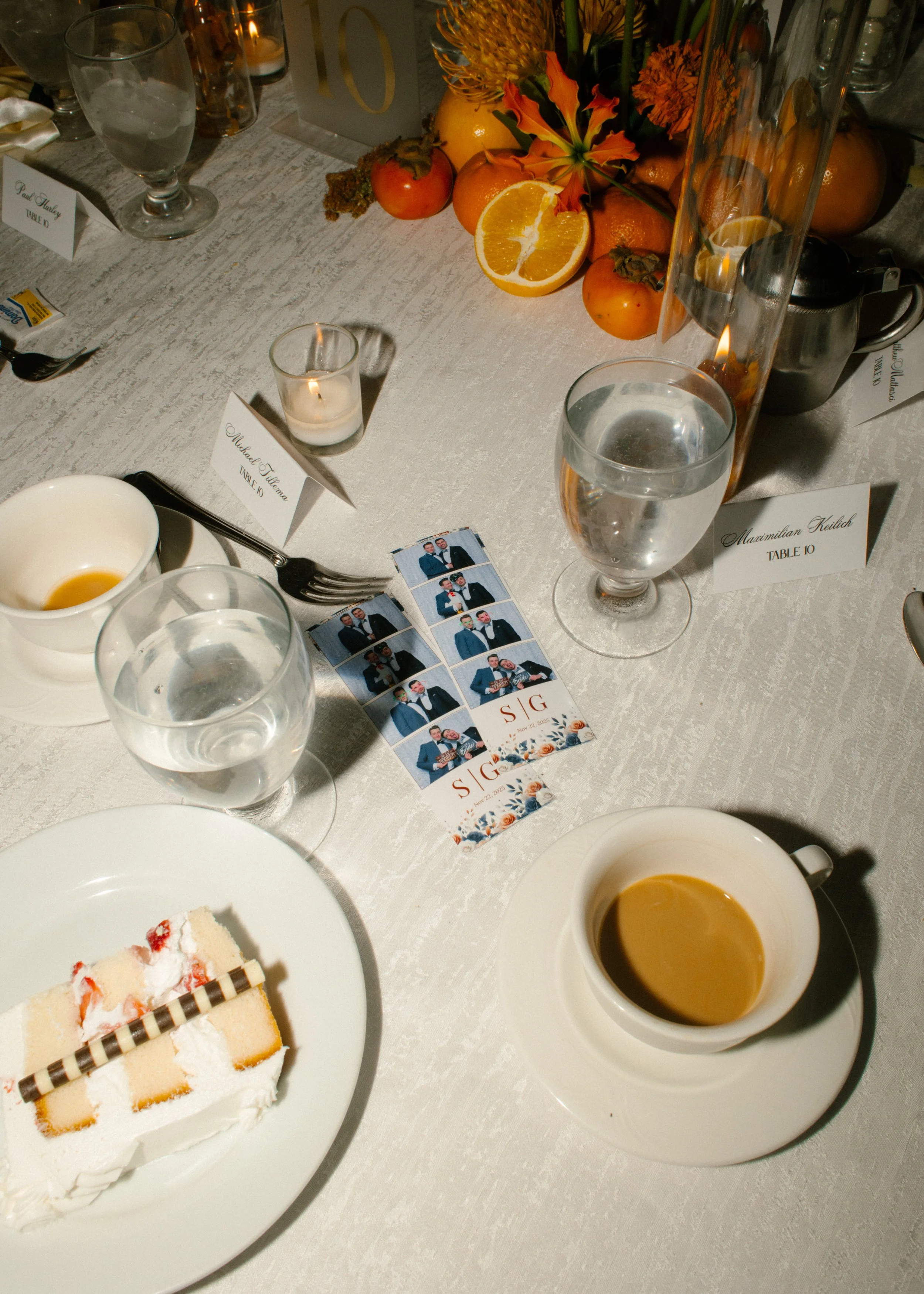 Wedding reception table featuring cake, coffee, candles, citrus-inspired centerpiece, and photo booth strips