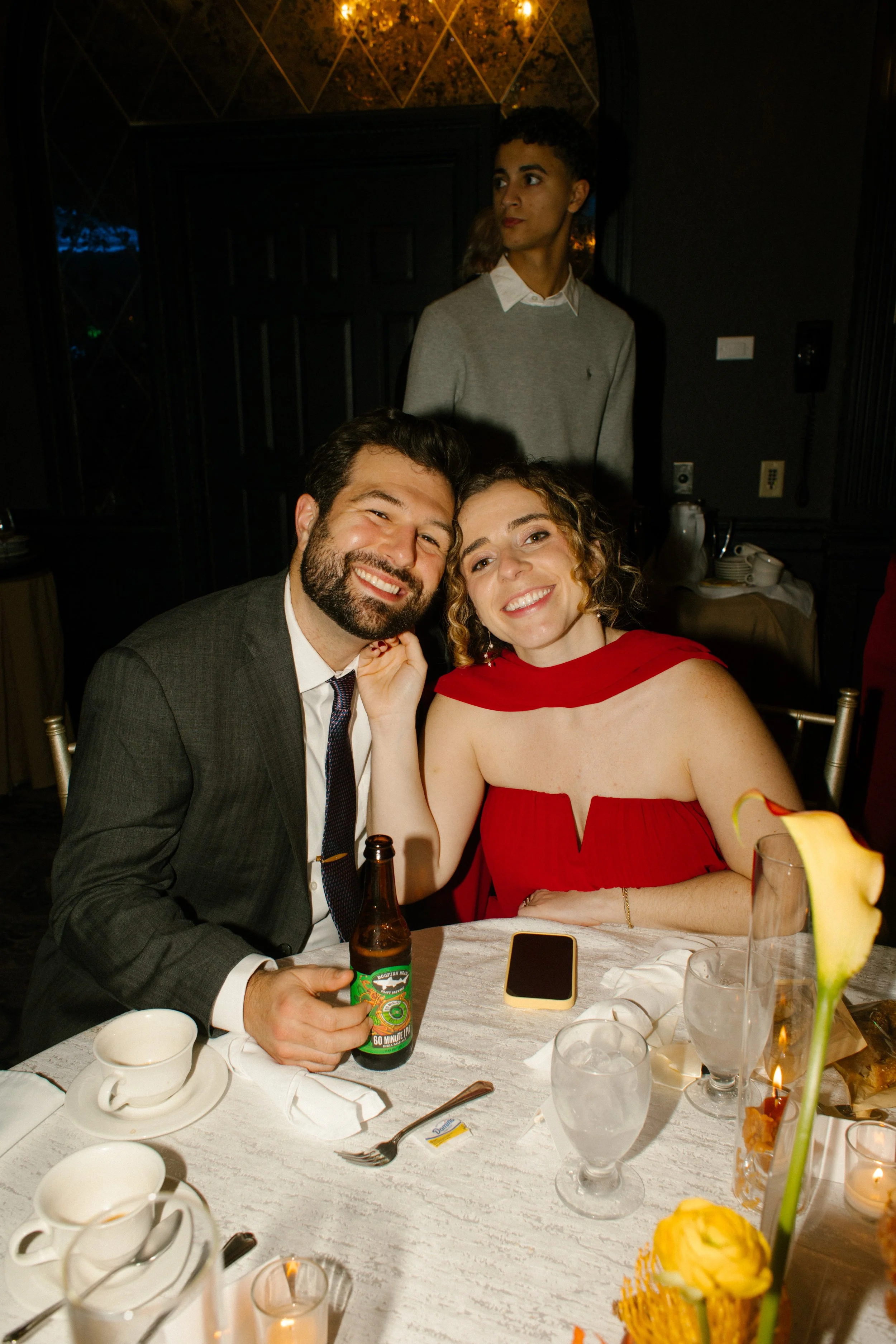 Wedding guests smiling for a portrait at their reception table during an elegant evening wedding celebration