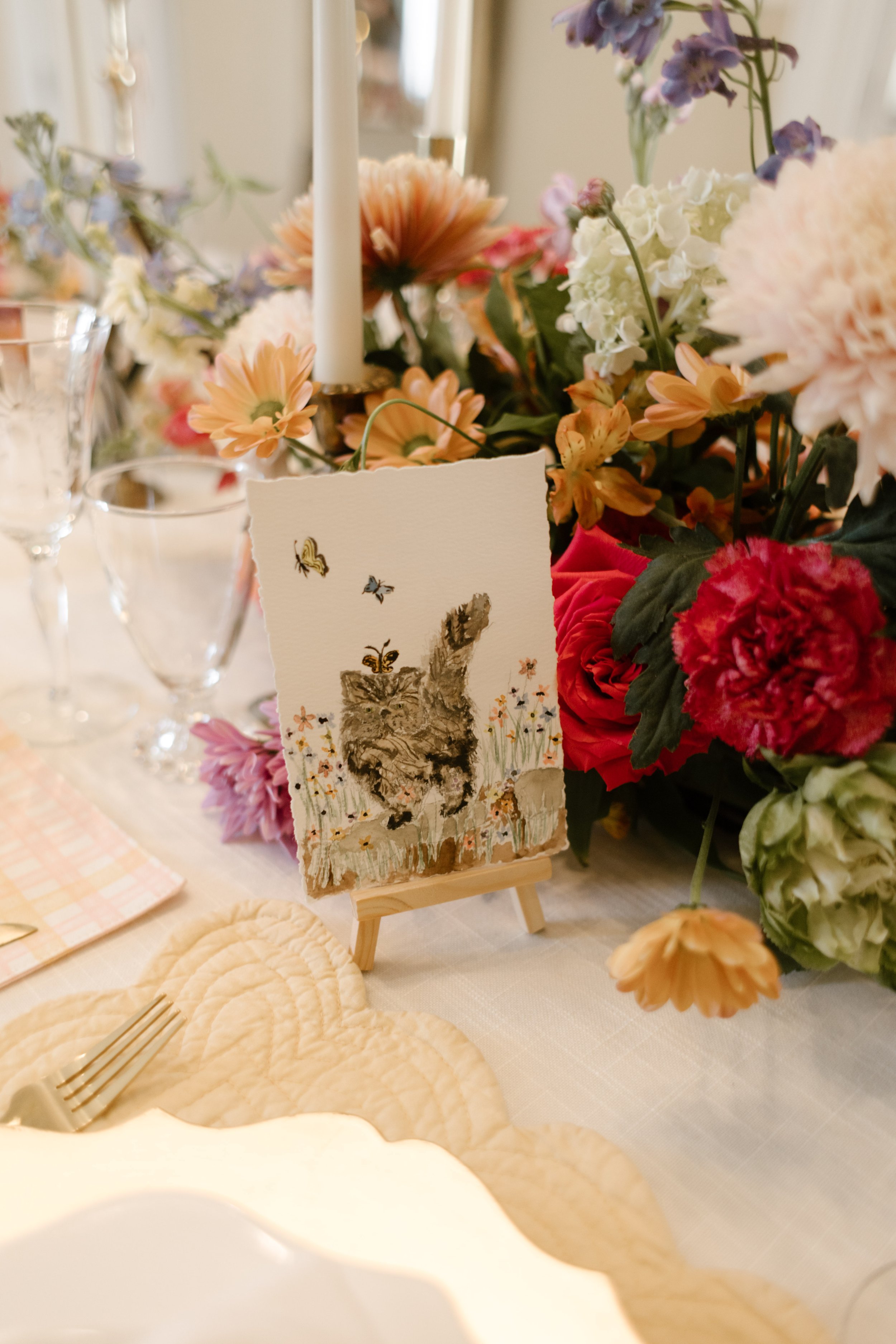 Hand-painted animal table number displayed among vibrant floral centerpieces