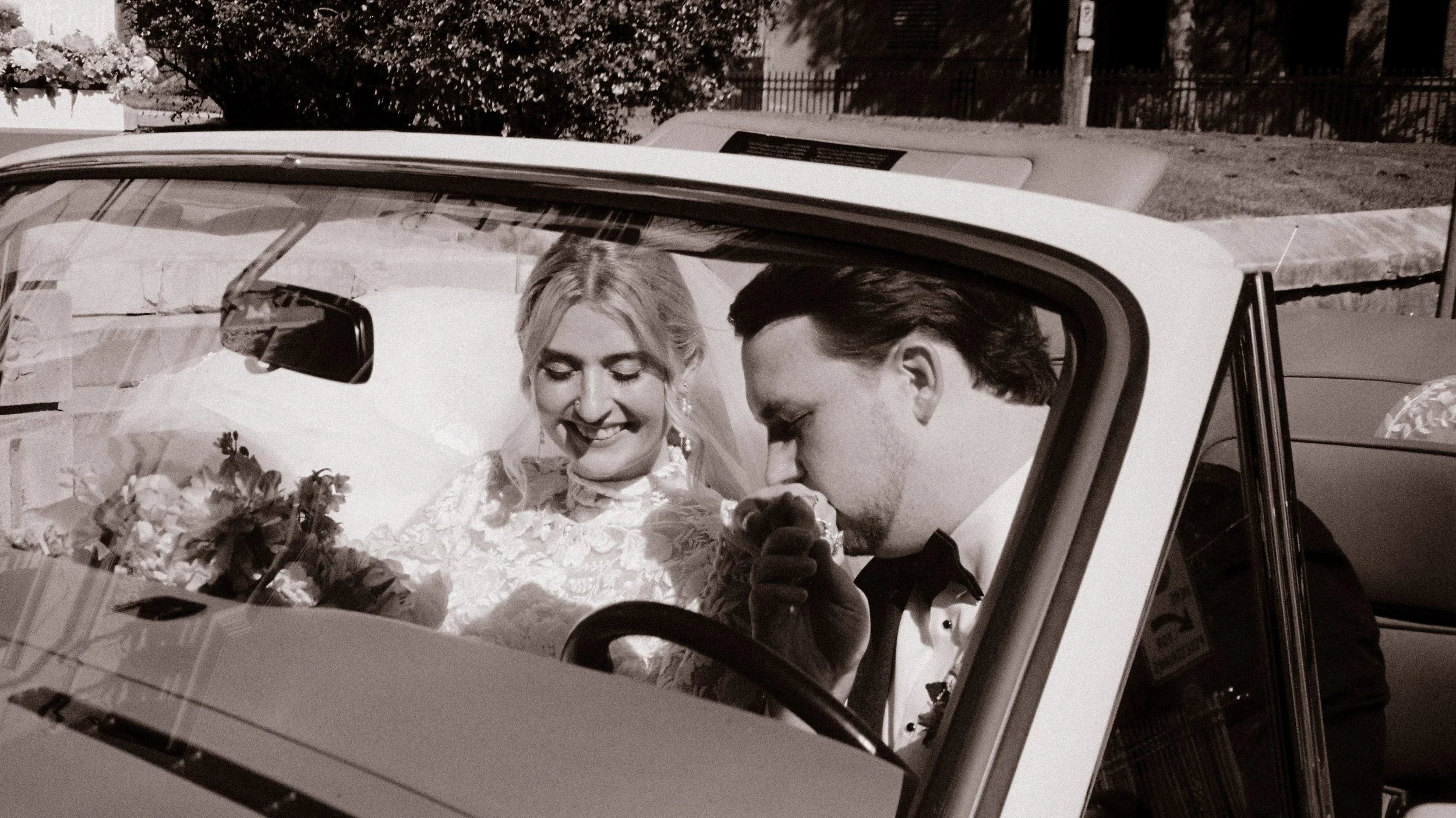 Black-and-white portrait of the bride and groom sharing a quiet moment in a classic wedding car