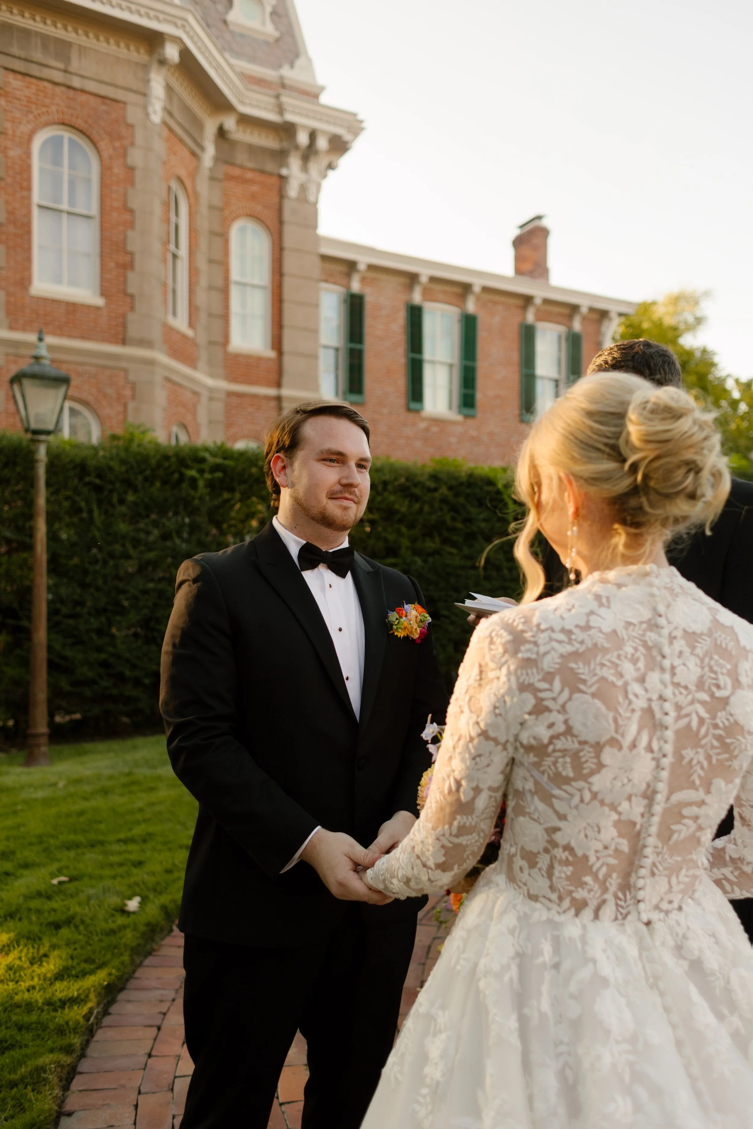 Bride and groom holding hands during their outdoor wedding ceremony in a historic garden setting