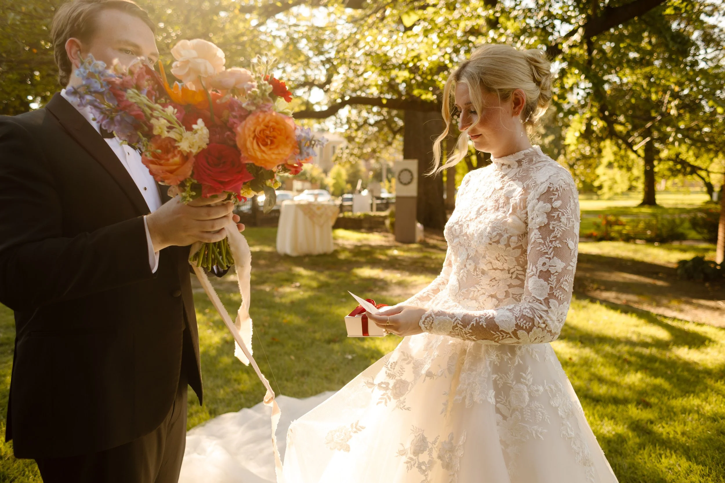 Bride opening a heartfelt wedding gift while the groom holds a vibrant garden-inspired bouquet