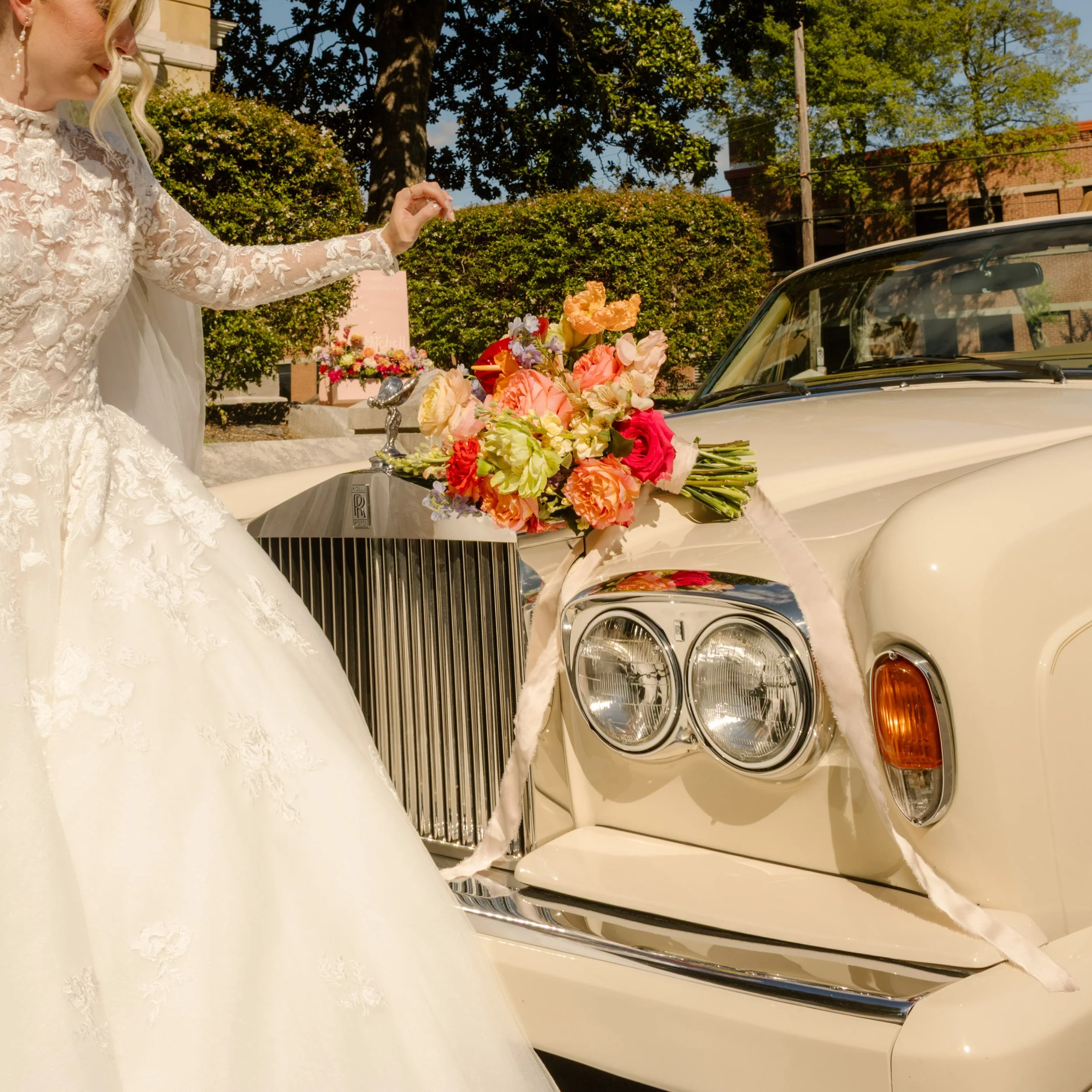 Colorful bridal bouquet resting on a vintage Rolls-Royce, showcasing bold floral palettes featured in 2027 wedding trends