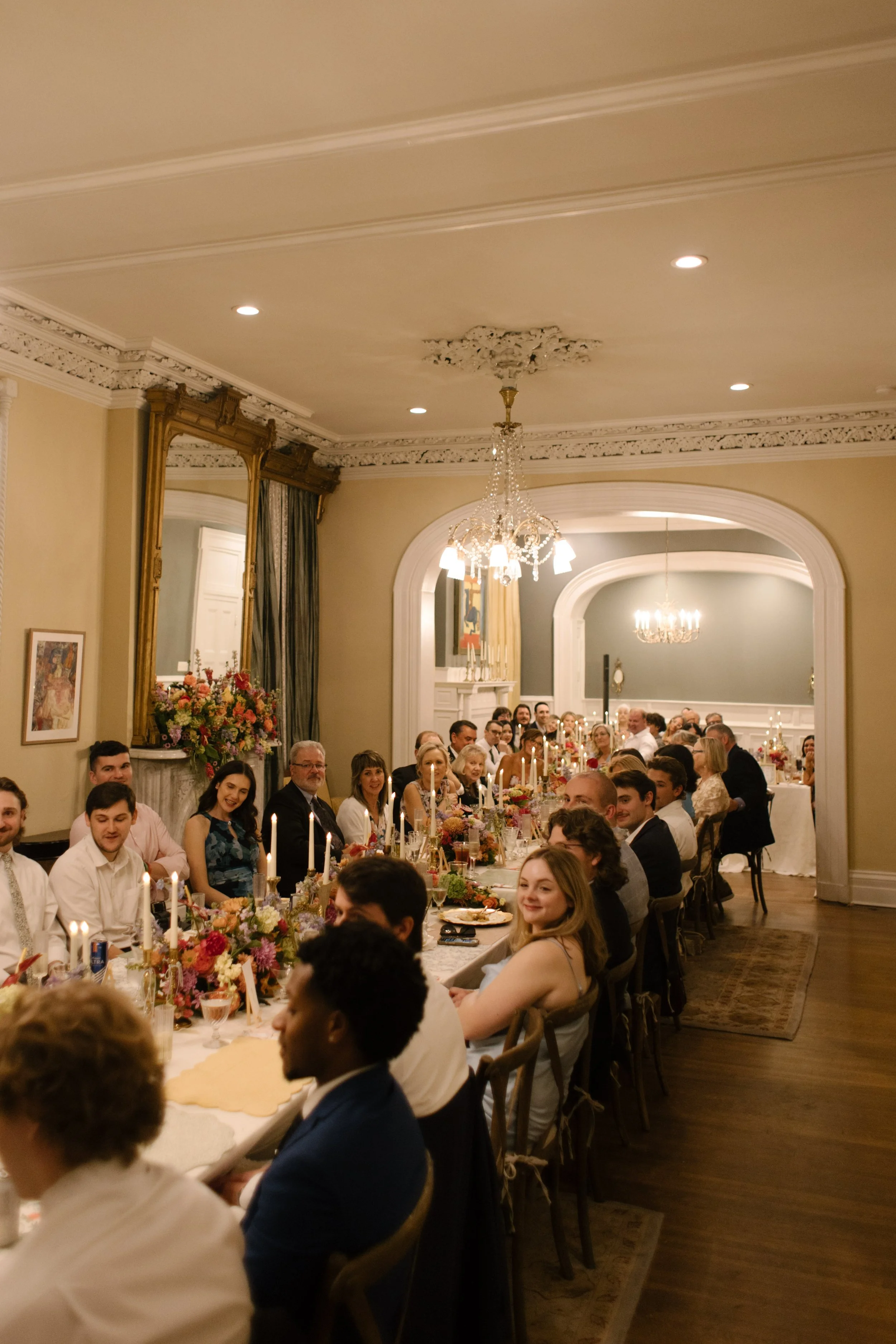 Guests gathered around a long reception table with colorful florals and candlelight, a signature look among 2027 wedding trends