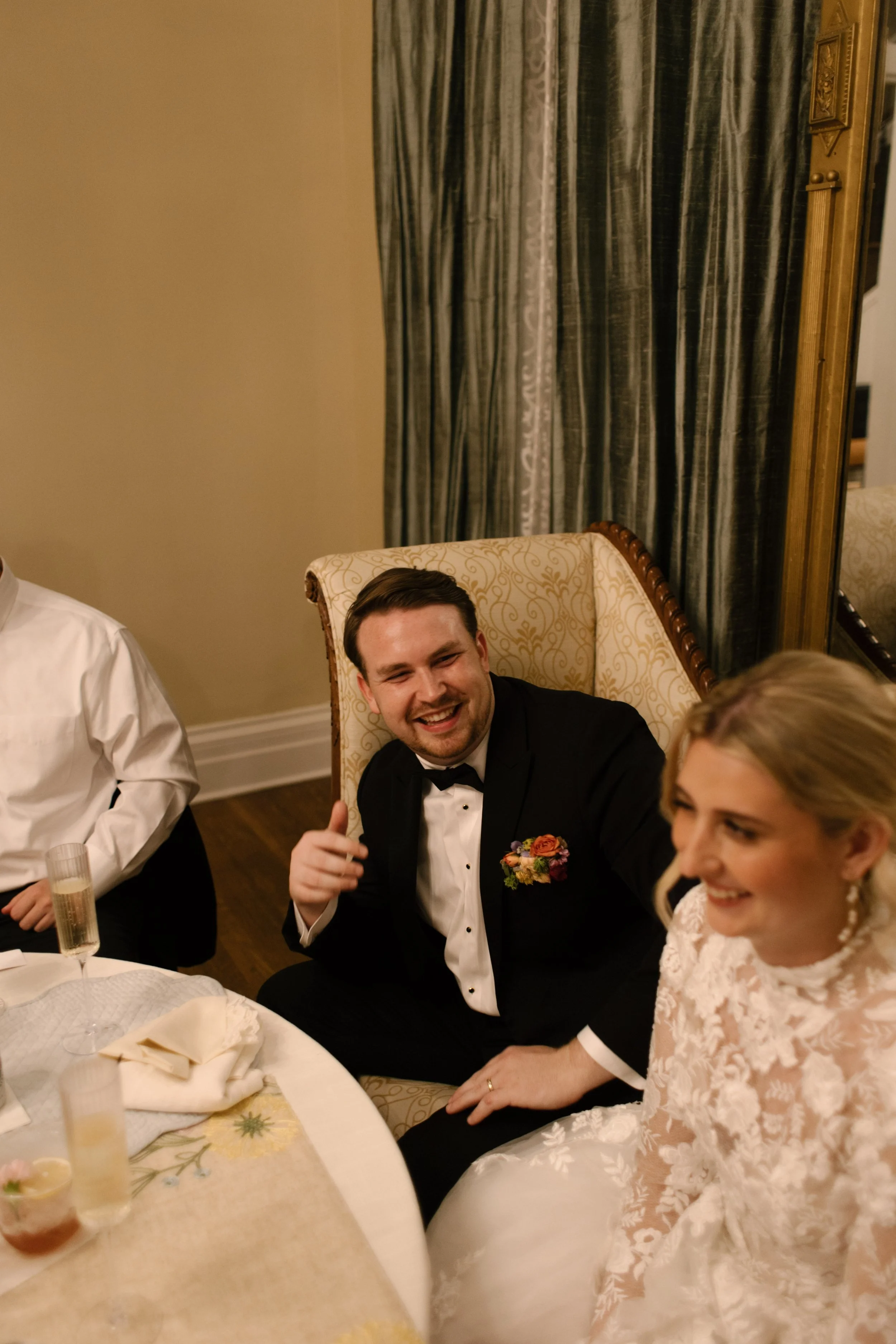 The newlyweds sharing a laugh during speeches surrounded by family and friends at their wedding reception