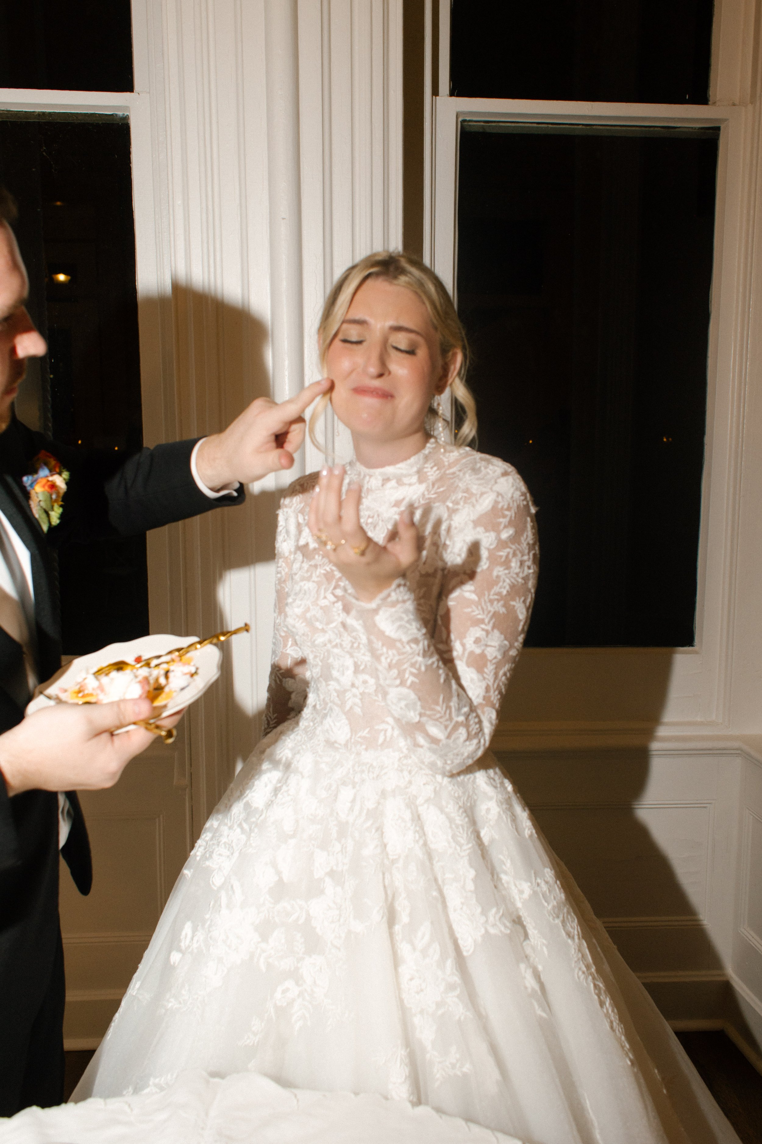 A playful cake-cutting moment between newlyweds showcasing candid wedding photography at its best