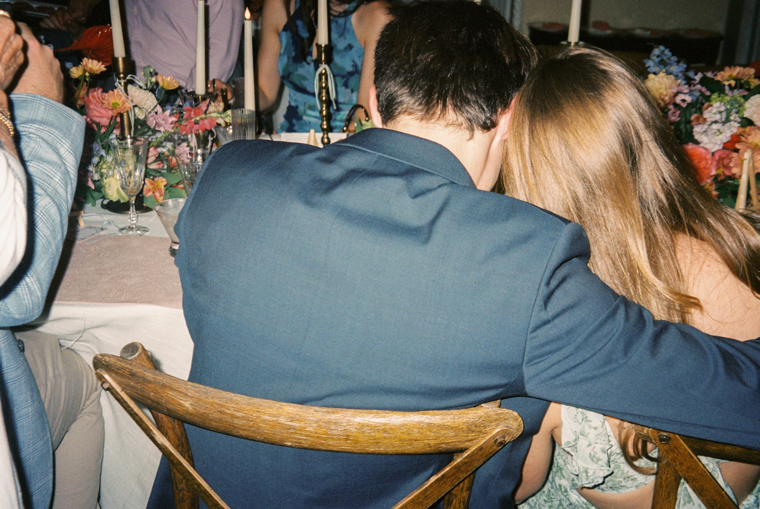 Guests sharing a quiet moment together at the reception surrounded by vibrant florals and warm candlelight