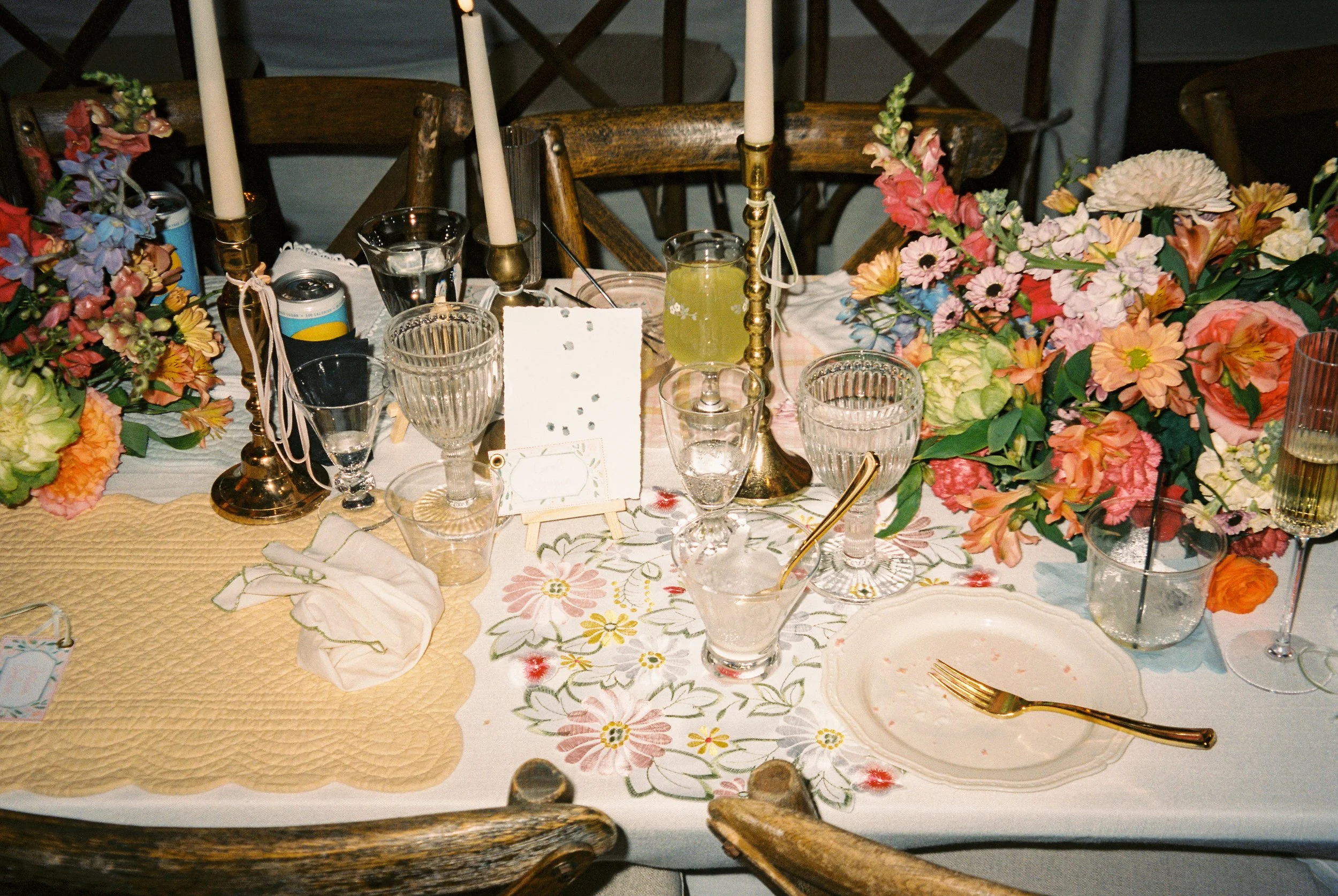 Romantic wedding table décor featuring colorful floral arrangements, taper candles, and personalized details