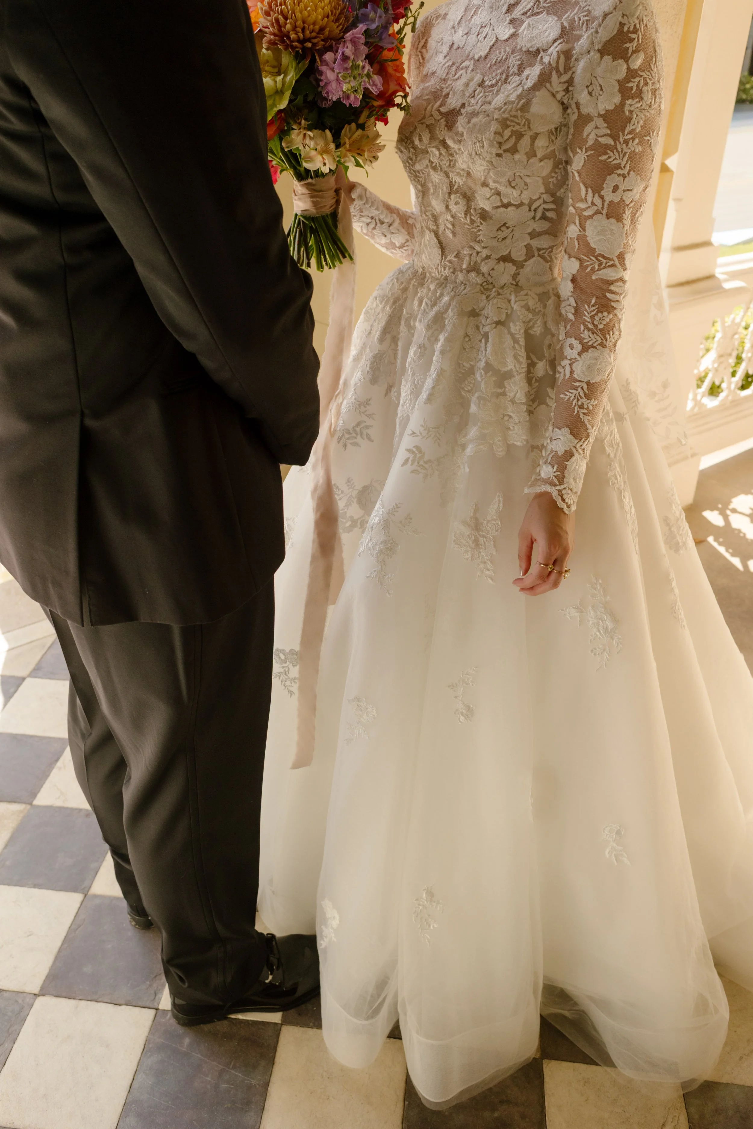 Romantic wedding details highlighting the intricate floral lace, bouquet, and soft afternoon light