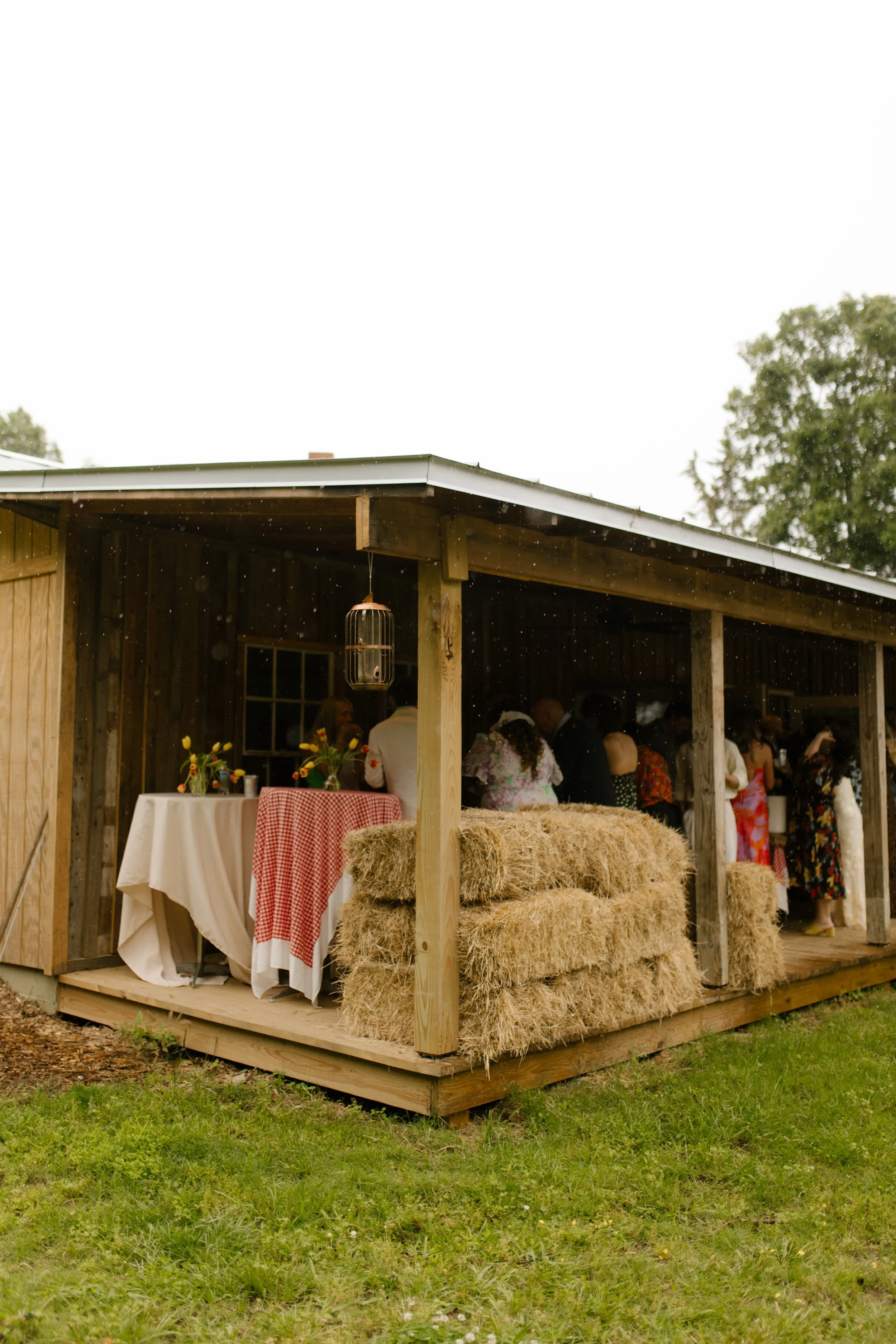 Rustic outdoor venue decorated with hay bales and tables for a wedding rehearsal dinner