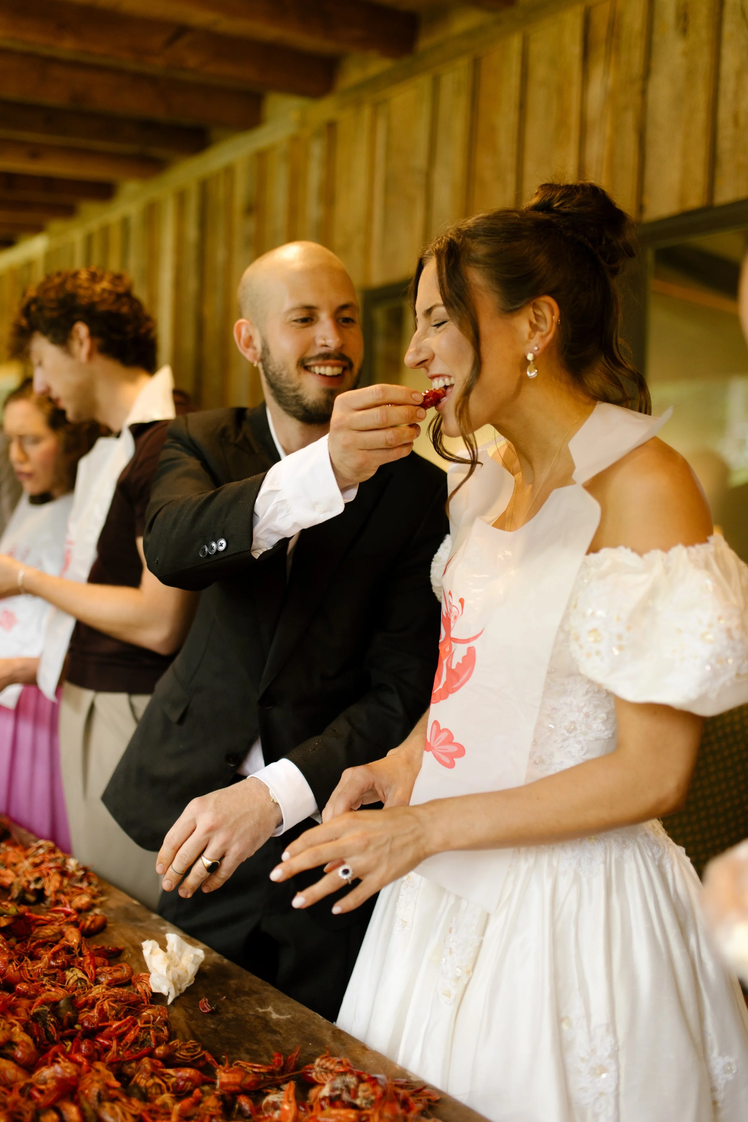 Groom feeding the bride crawfish during rehearsal dinner photography at a casual Southern wedding