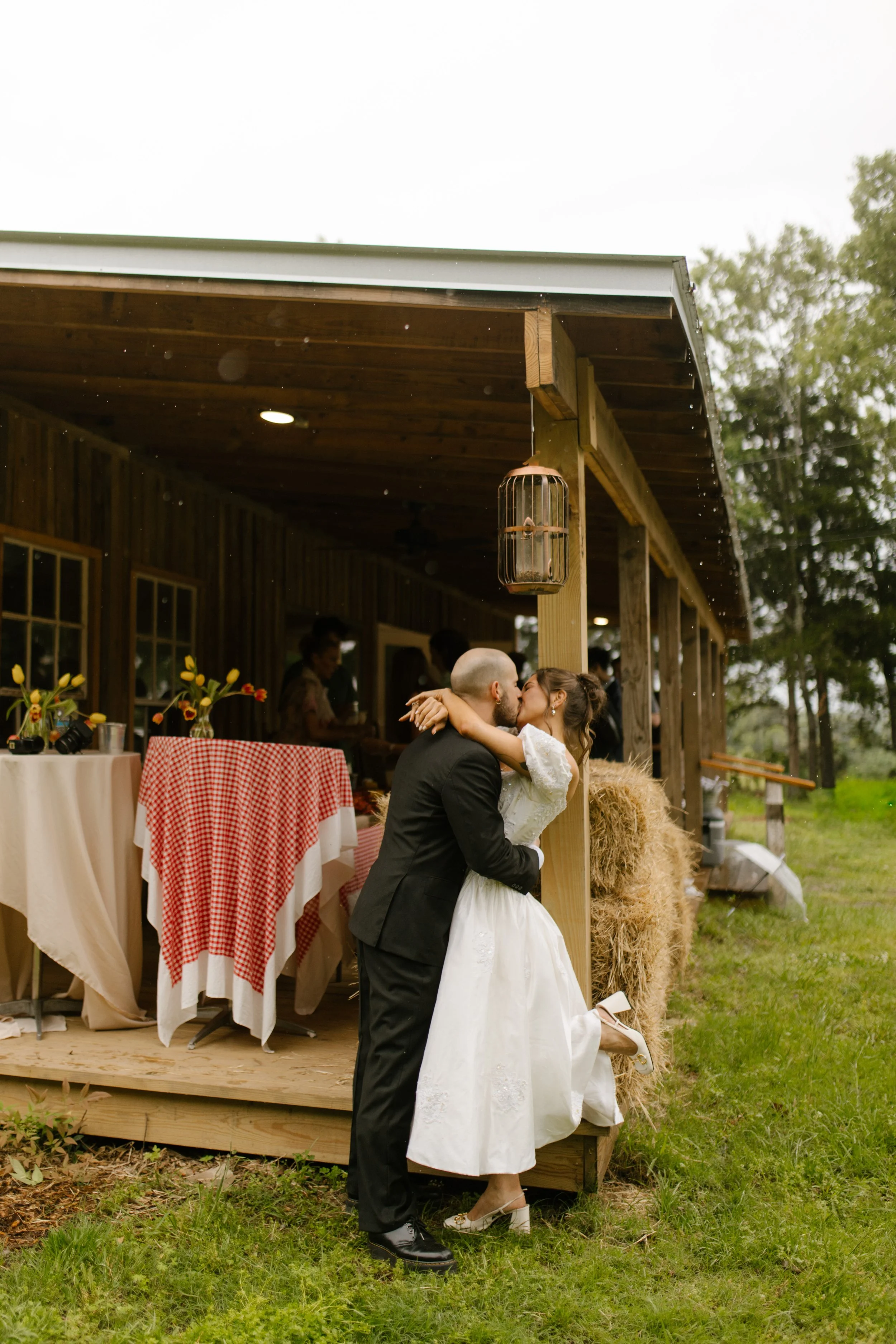 Couple sharing a kiss outside the venue during rehearsal dinner photography on a rainy wedding weekend
