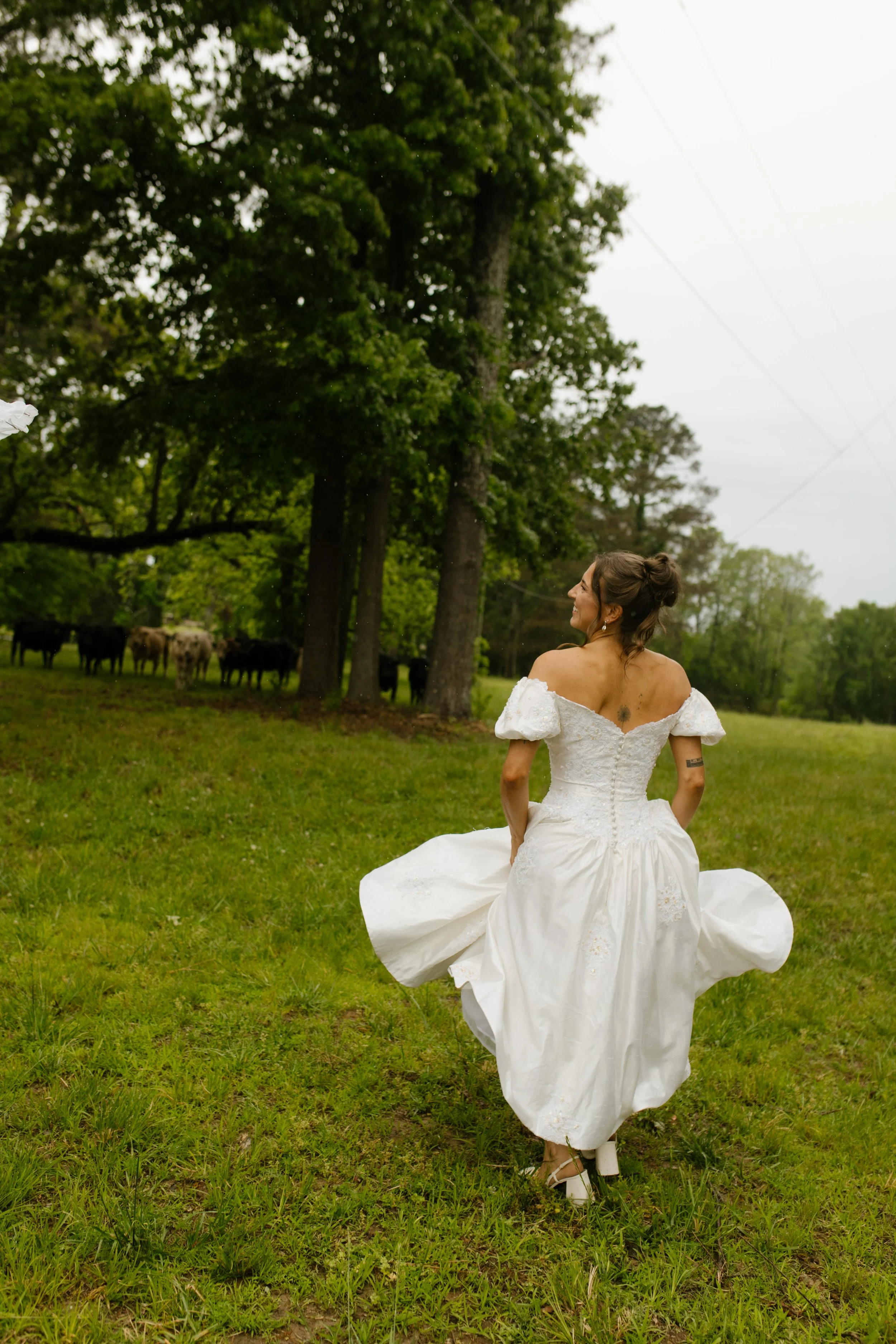 Bride walking through a grassy field in her wedding dress before the rehearsal dinner festivities