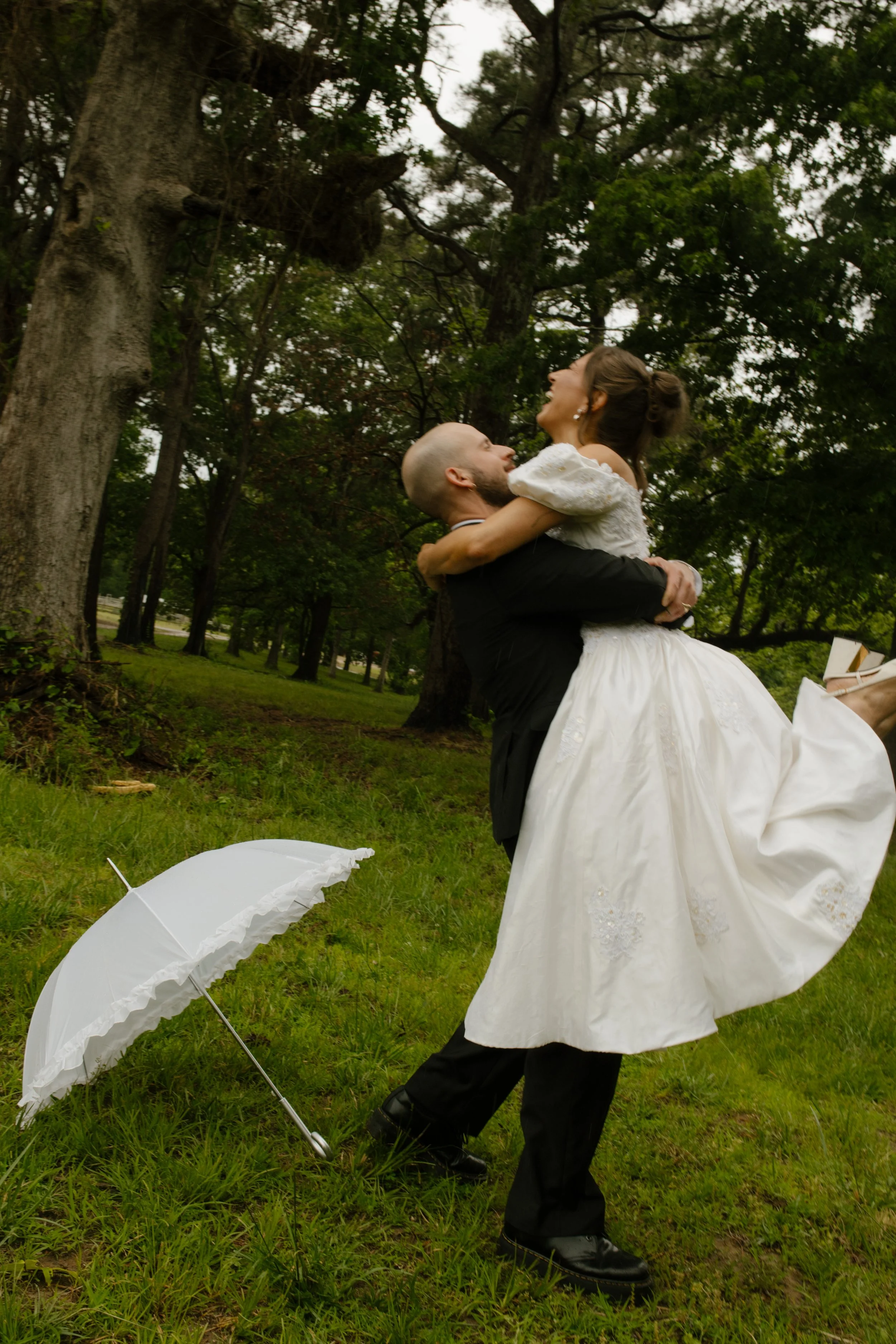 Groom lifting the bride in a grassy field during rehearsal dinner photography portraits