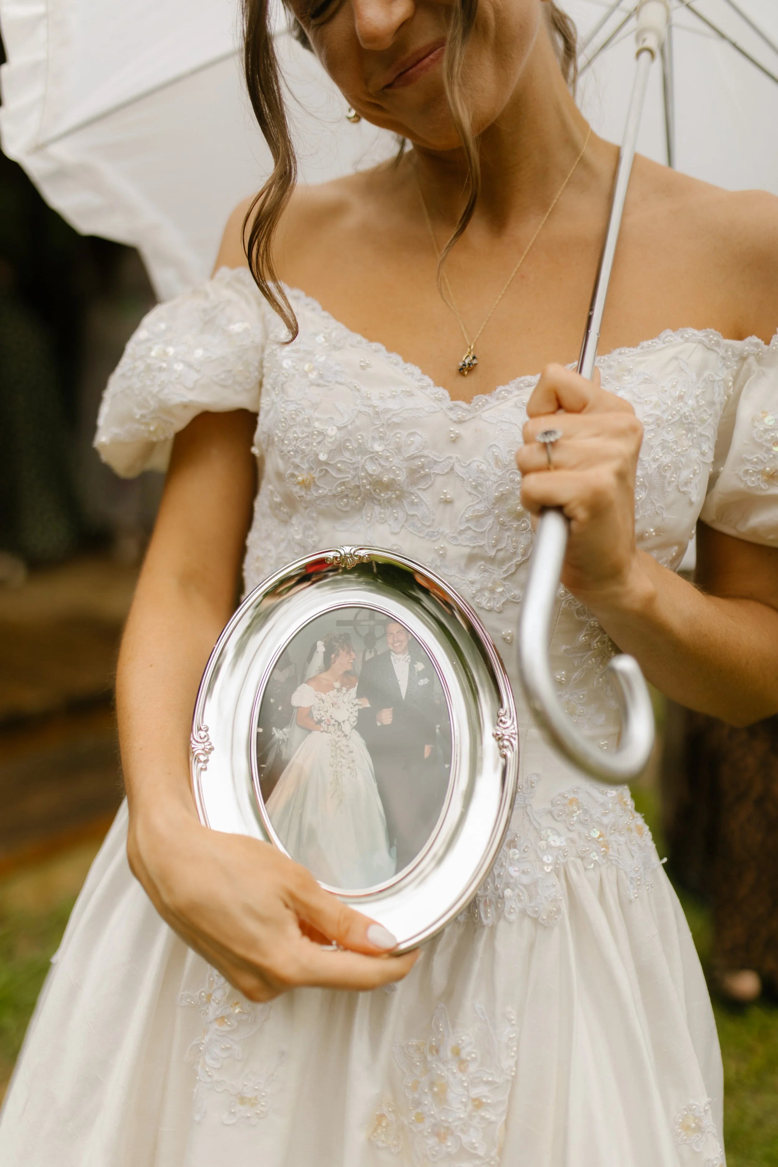 Bride holding a framed family wedding photo during rehearsal dinner photography before the crawfish boil
