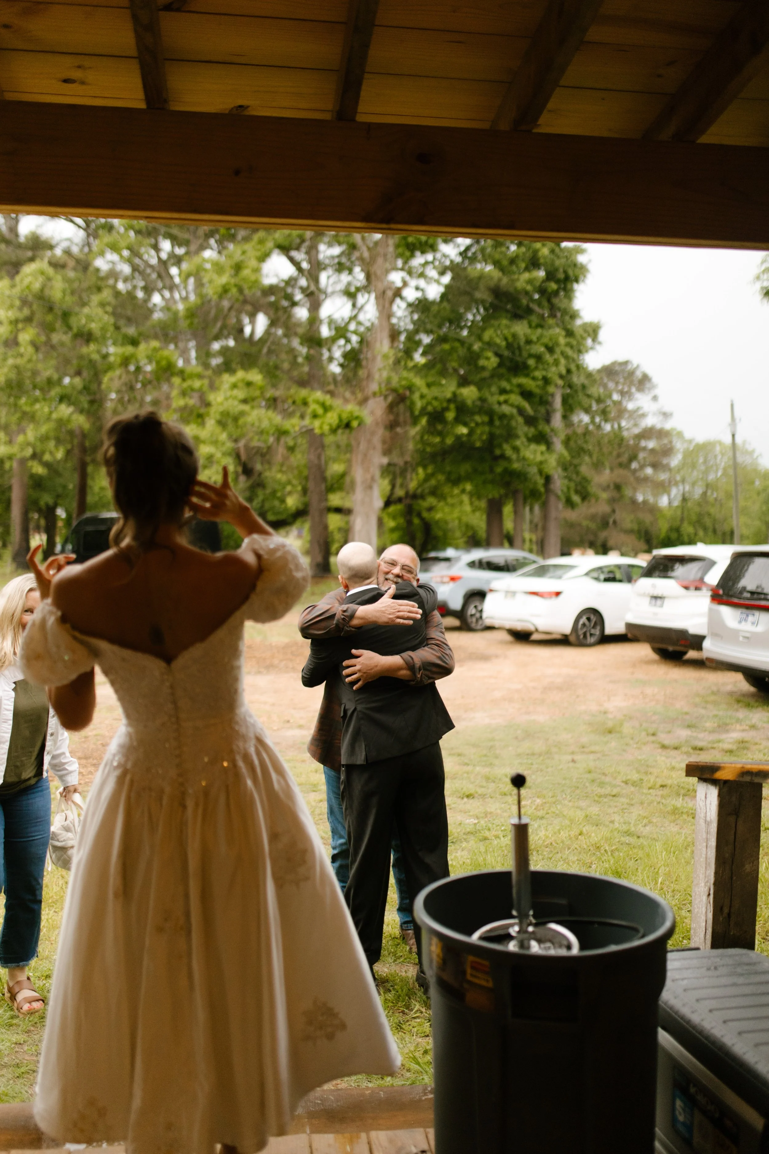 Groom hugging a family member as guests arrive for the wedding rehearsal dinner