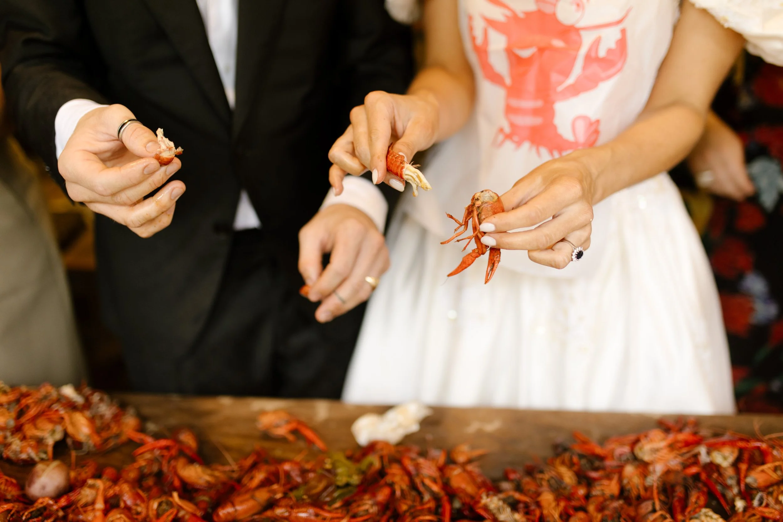 Bride and groom peeling crawfish together during rehearsal dinner photography coverage