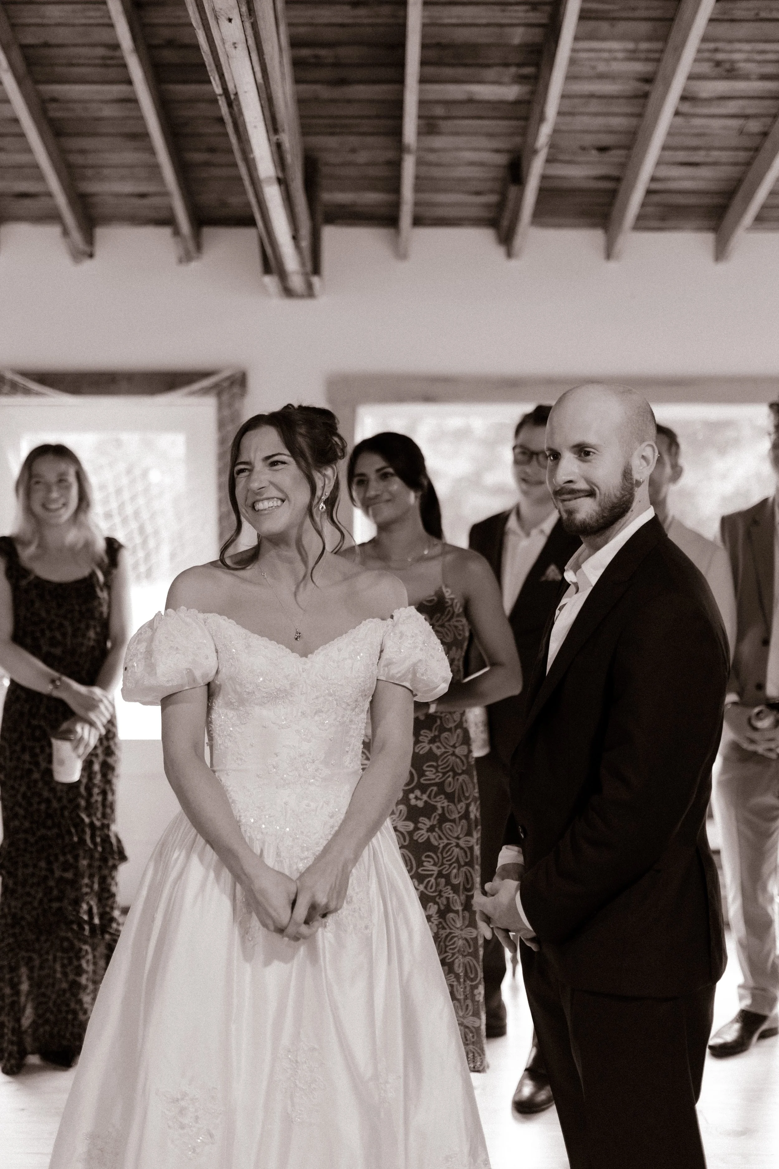 Bride and groom smiling with loved ones during an intimate indoor wedding rehearsal photography moment.