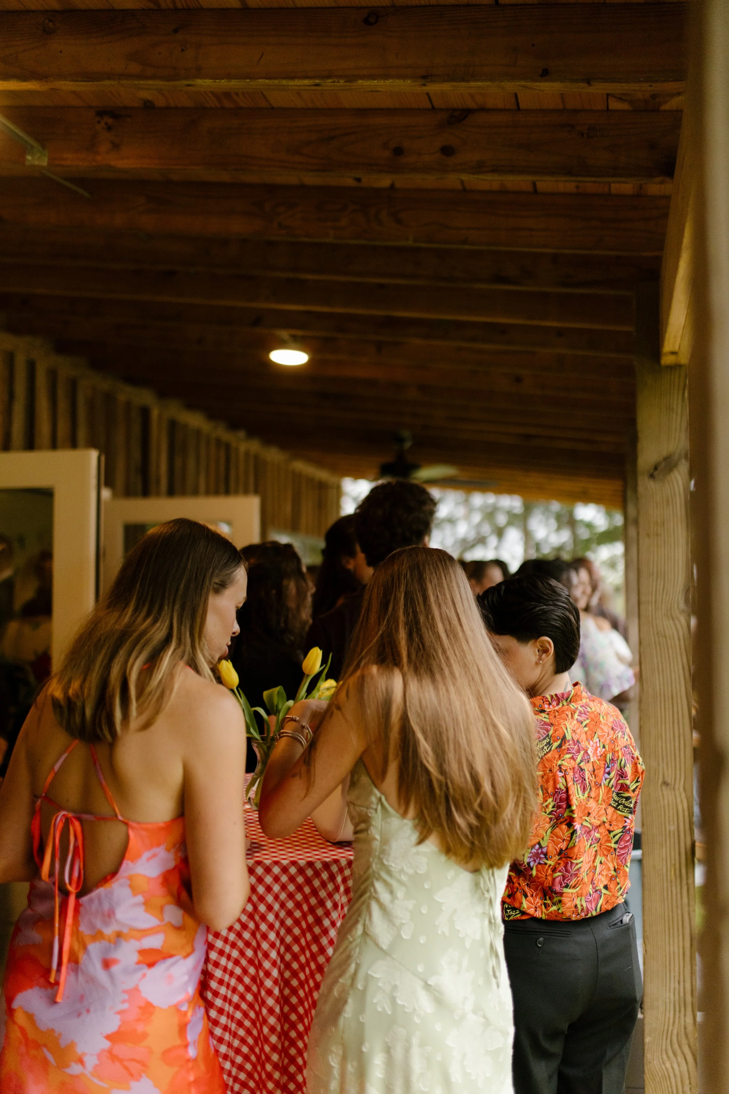 Friends chatting around a cocktail table on a covered porch during wedding rehearsal photography festivities.