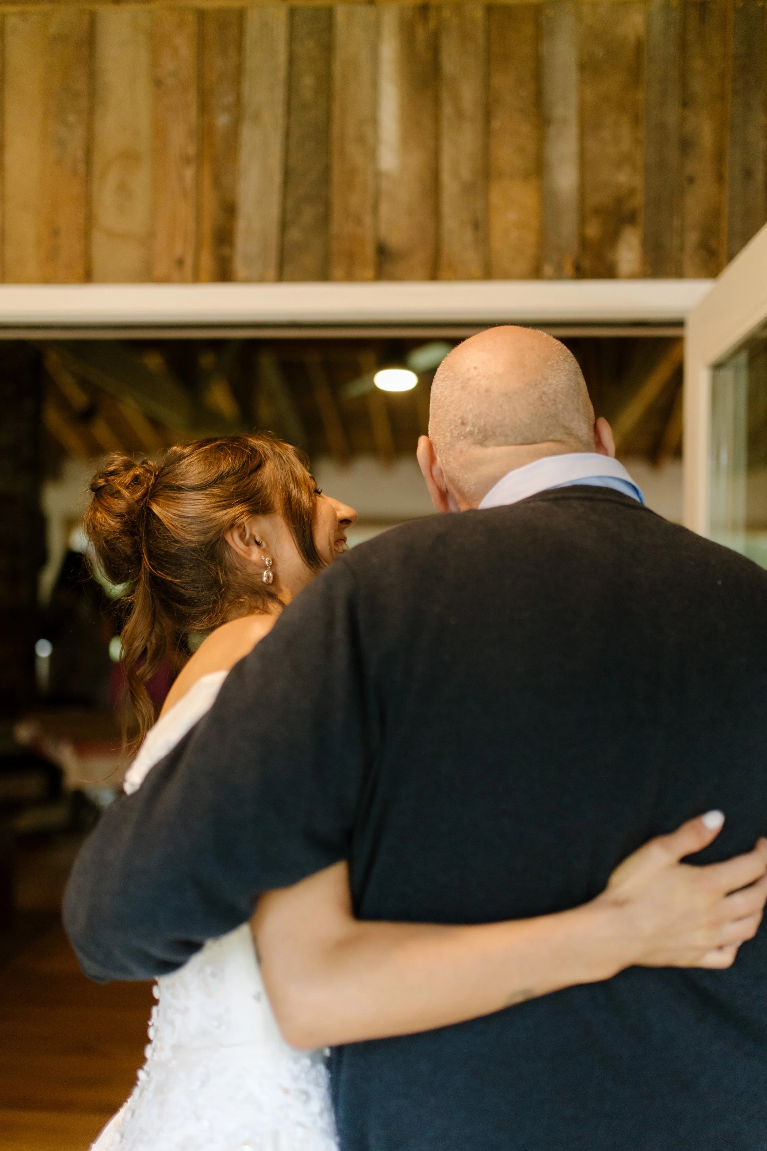 Bride sharing a warm embrace with a family member outside the venue before the rehearsal dinner.