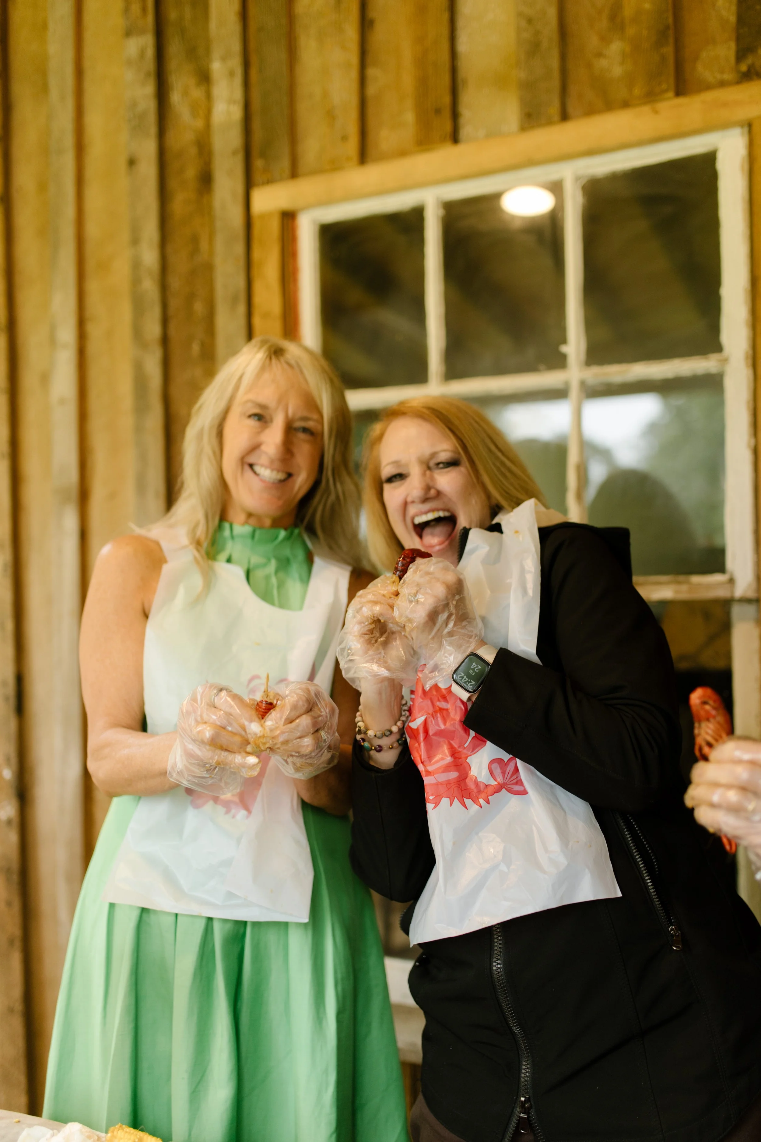 Guests wearing bibs and gloves enjoy a crawfish boil at a lively wedding rehearsal photography event.