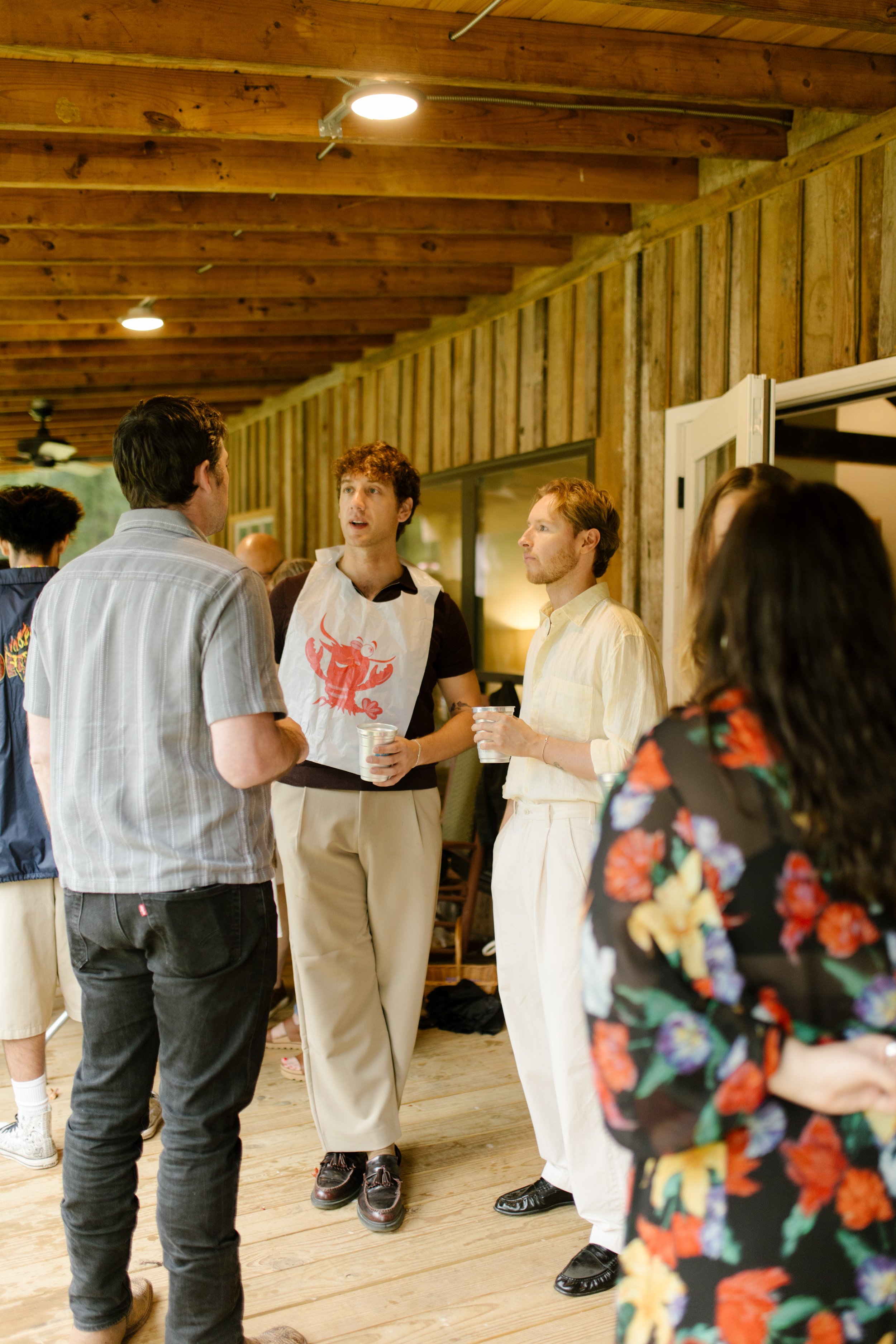 Wedding rehearsal photography guests mingling on a rustic covered porch before the celebration begins.