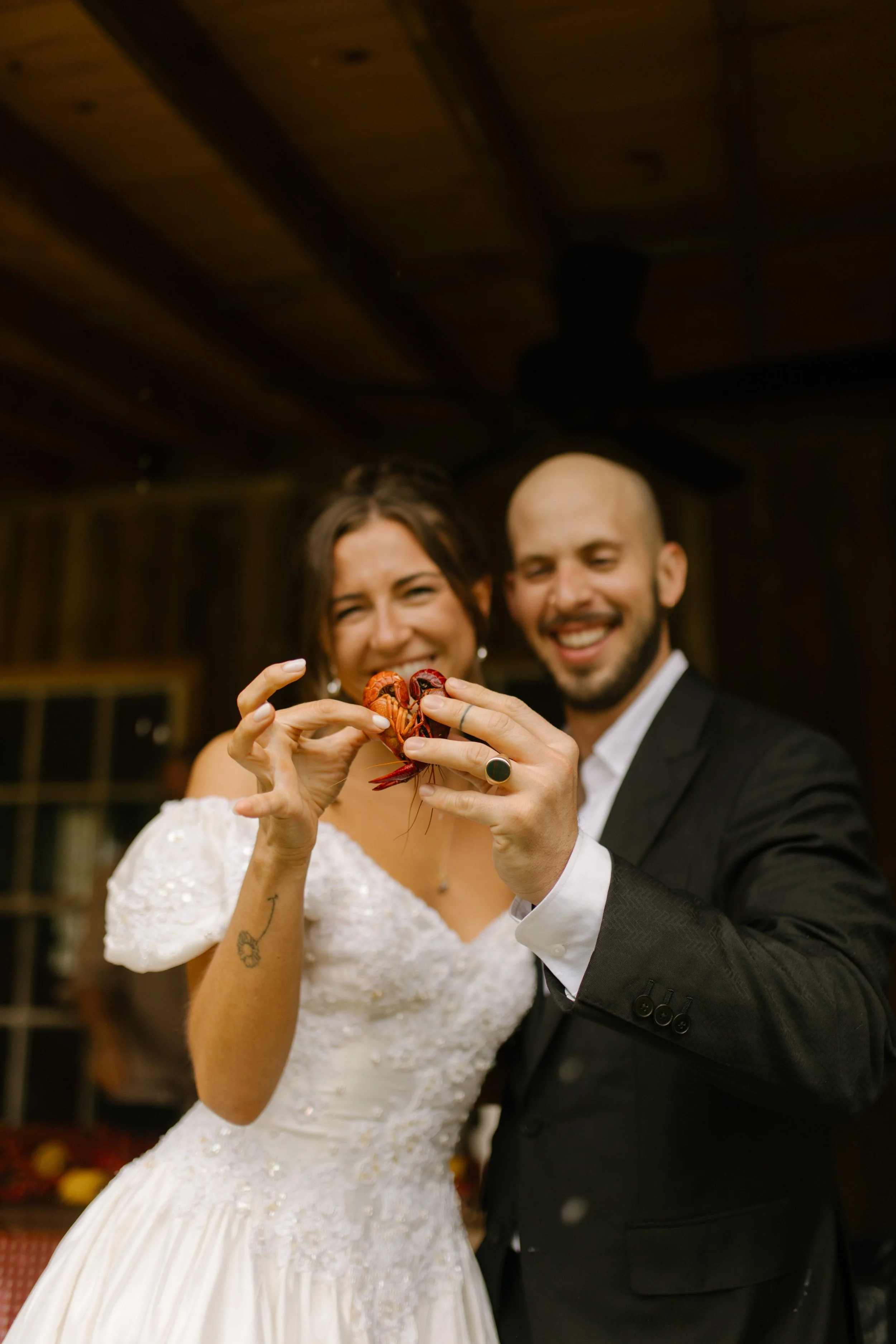 Bride and groom proudly holding a crawfish together during a fun wedding rehearsal dinner celebration.