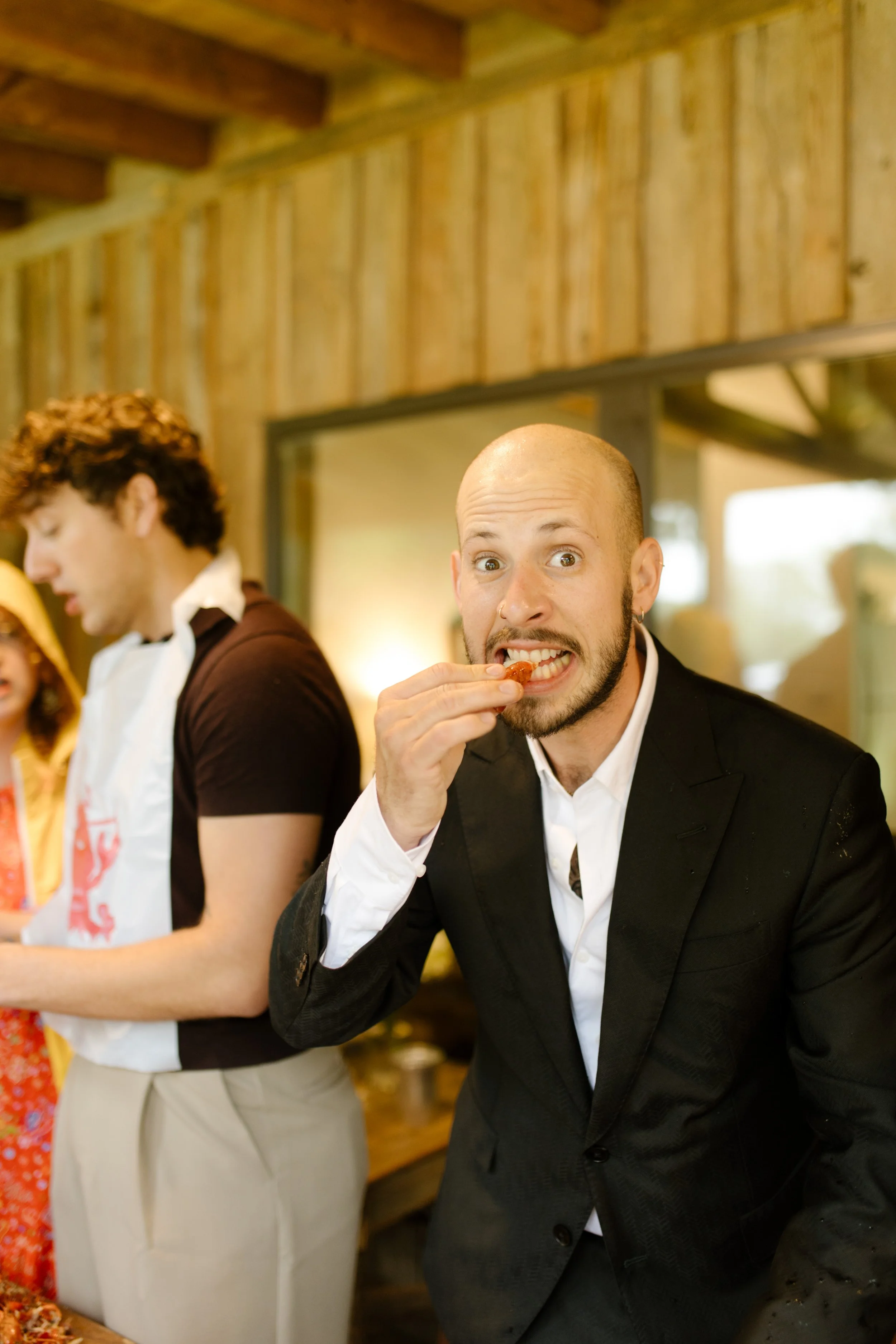 Groom eating crawfish while celebrating with guests during rehearsal dinner photography