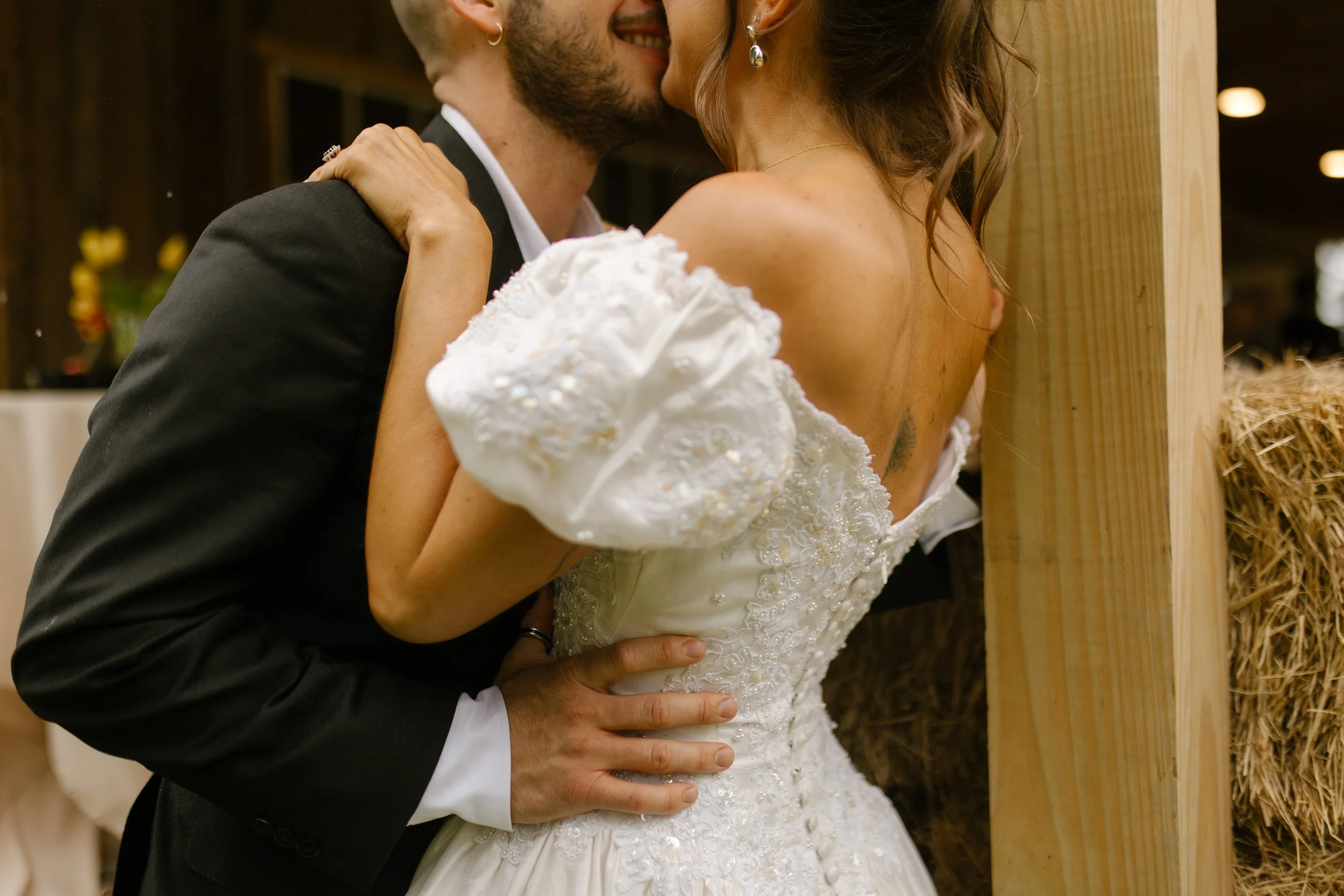 Bride and groom embracing near a rustic barn entrance during an intimate wedding rehearsal photography moment.
