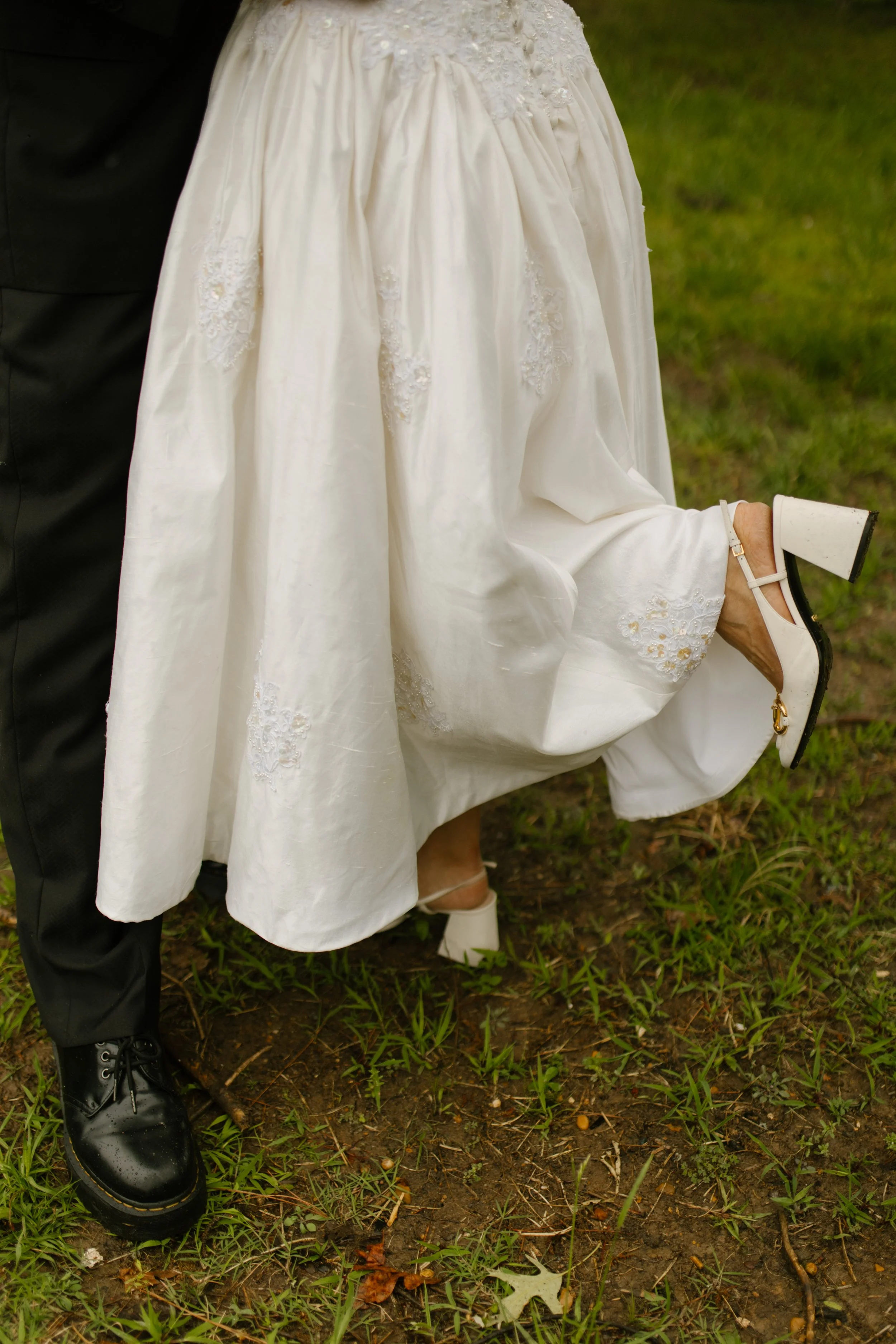 Close-up of a vintage-inspired wedding dress and white heels during rehearsal dinner photography