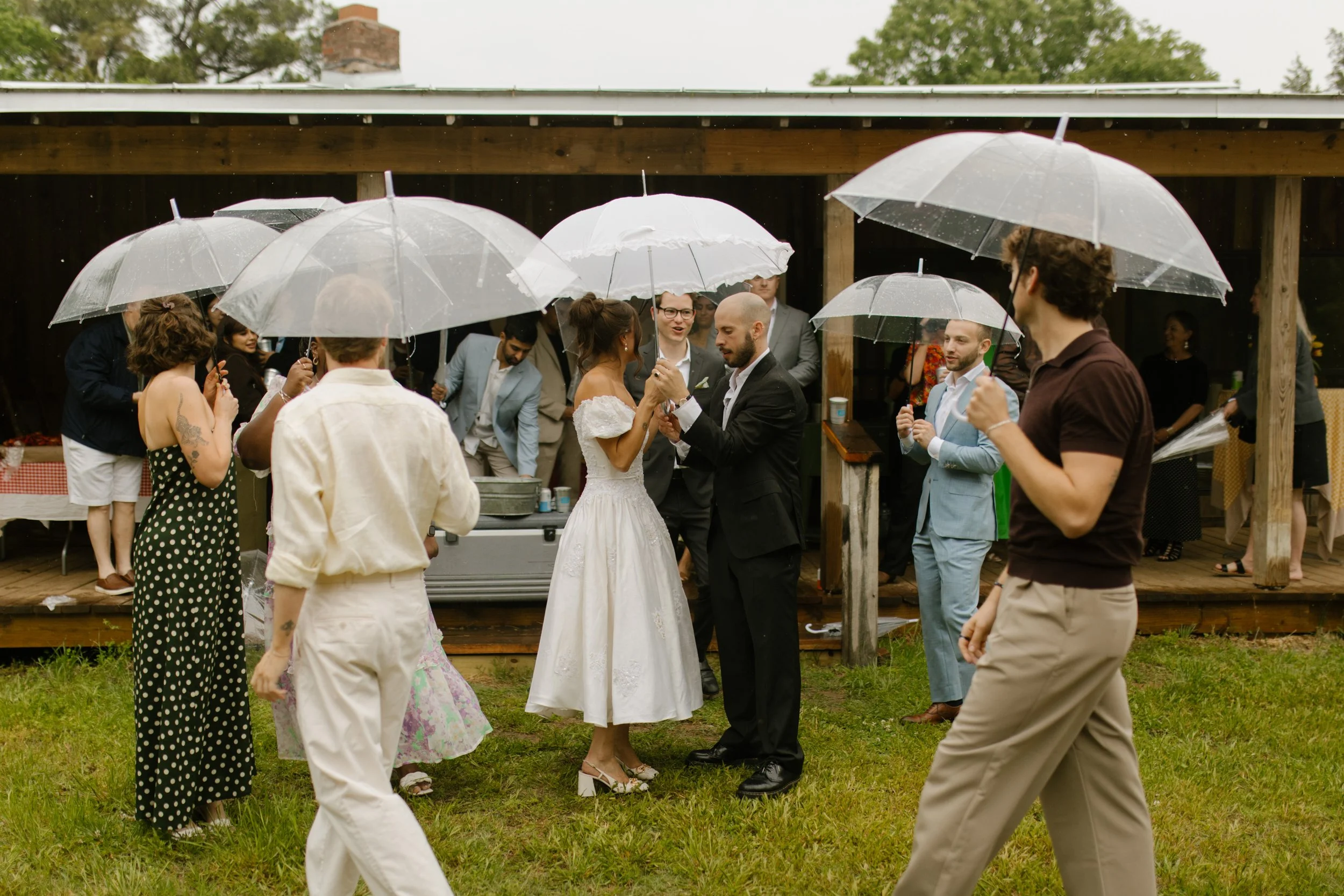 Guests gathered under clear umbrellas outside the venue during rehearsal dinner photography