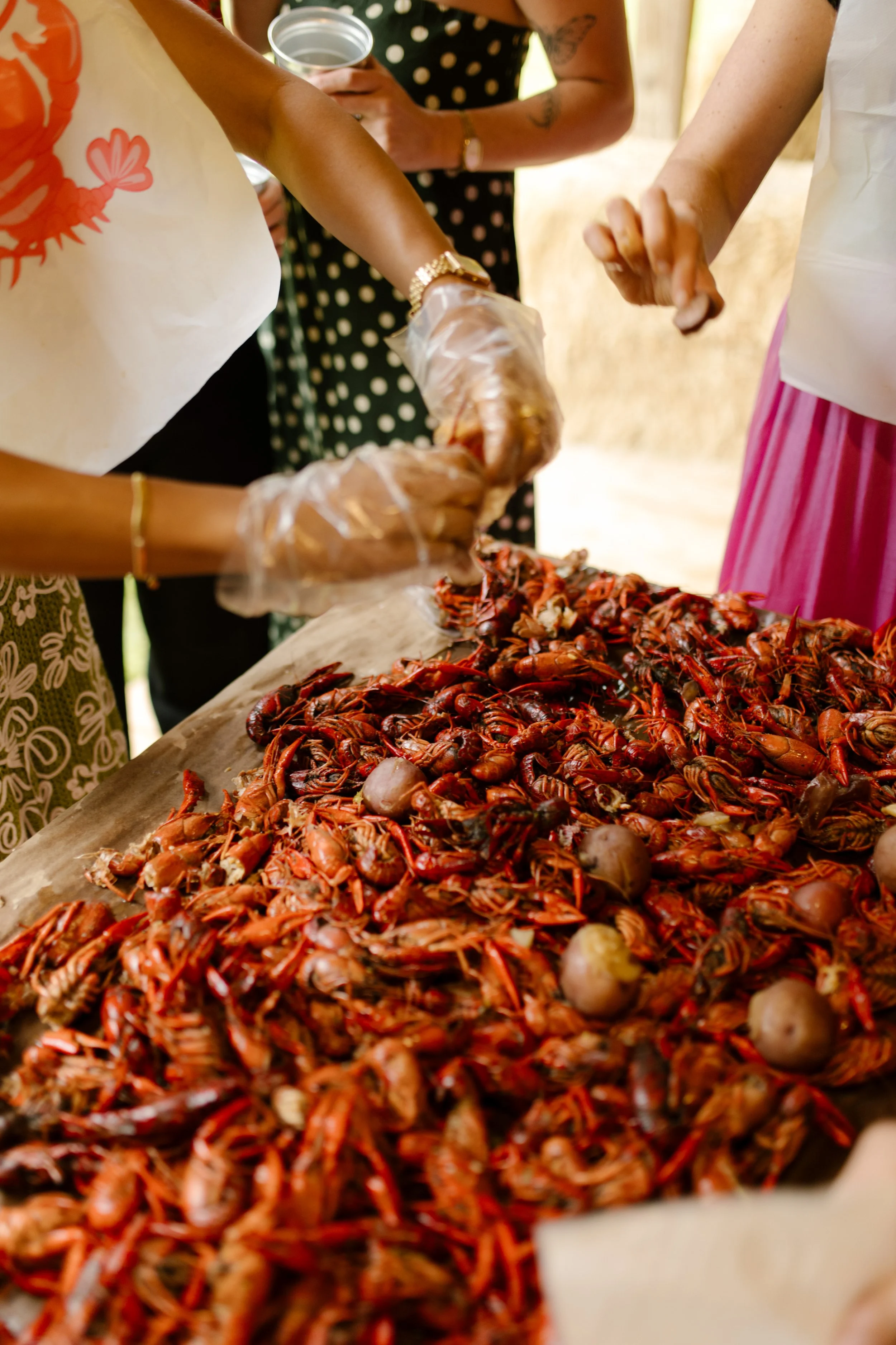 Guests wearing bibs and gloves peeling crawfish around a communal table at the rehearsal dinner.