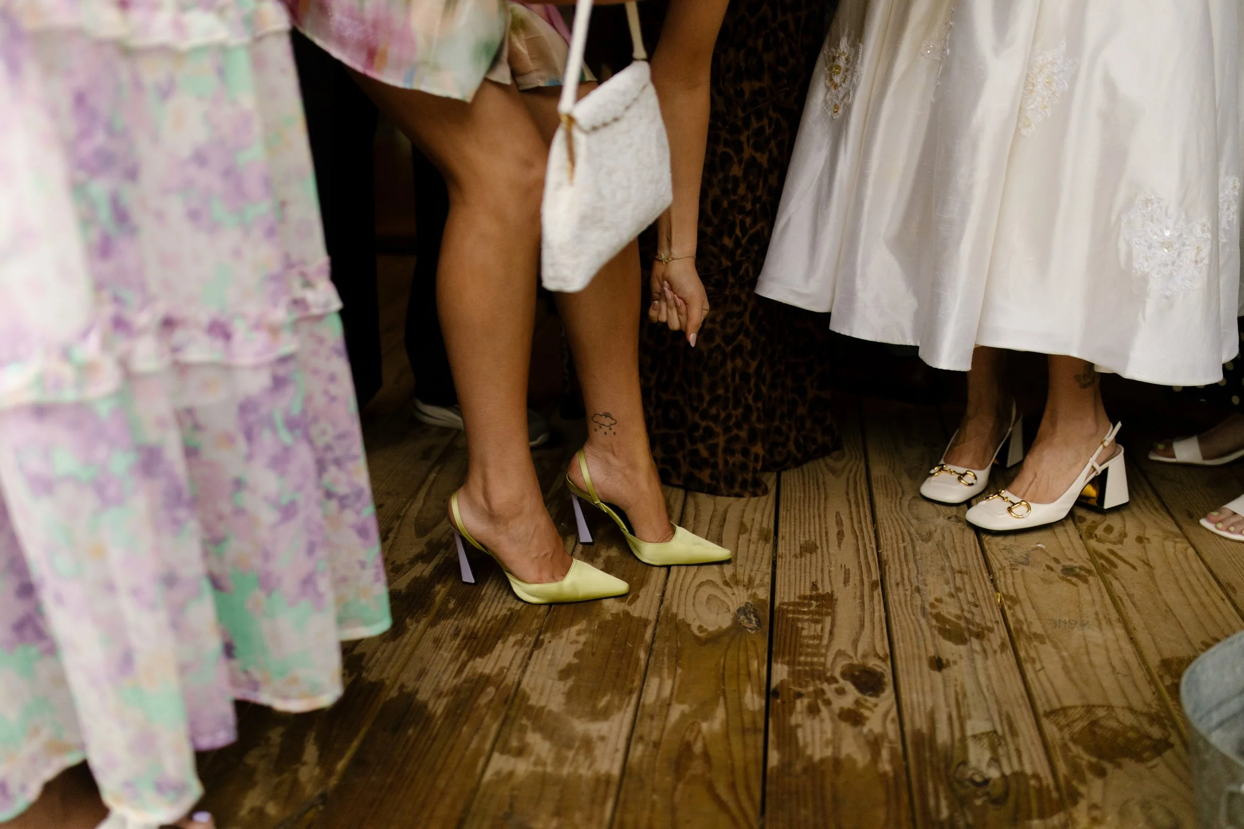 Guests gathered on a rain-speckled porch, showcasing colorful heels and wedding rehearsal dinner fashion.