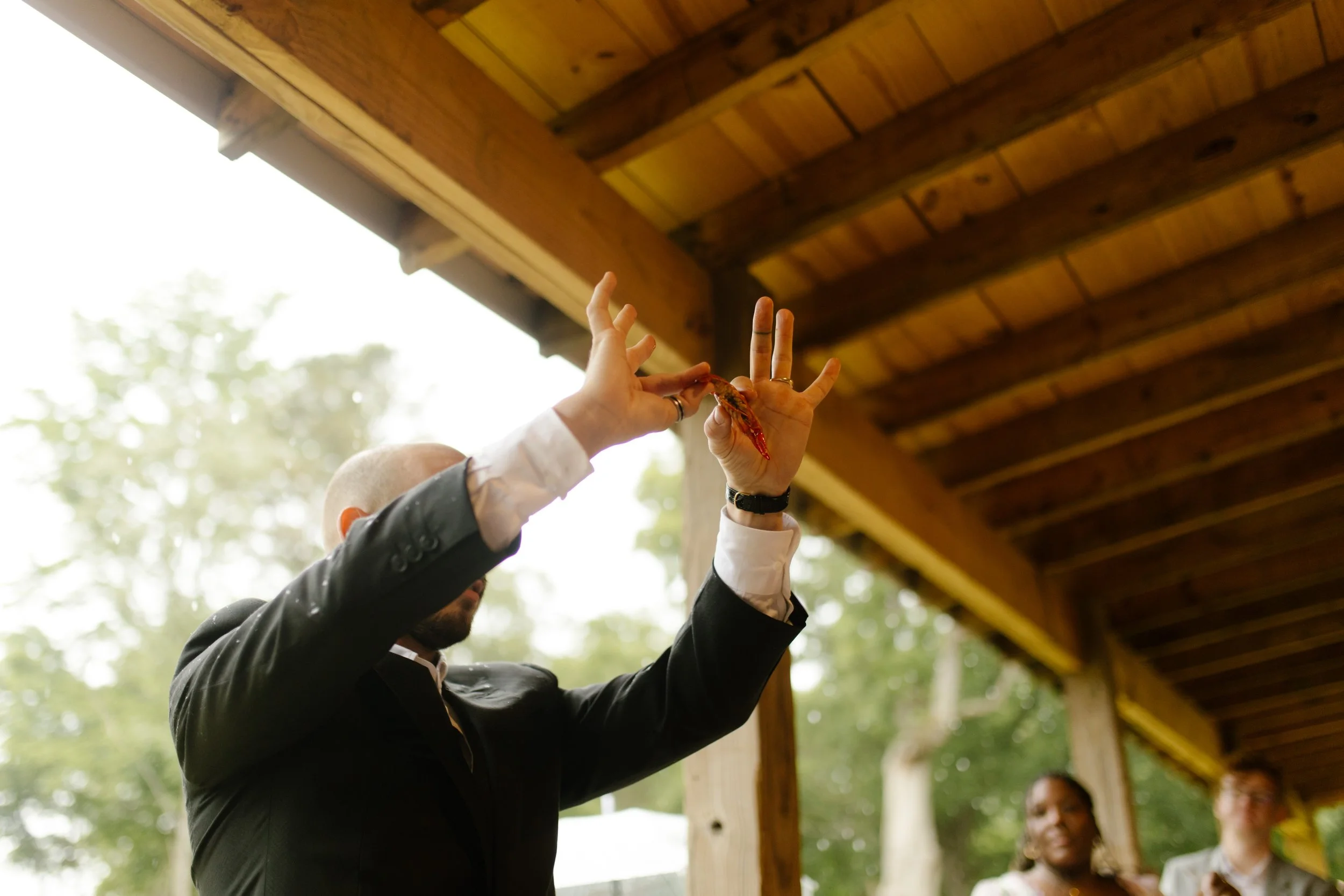 Groom holding up a crawfish while entertaining guests during a fun wedding rehearsal photography celebration.