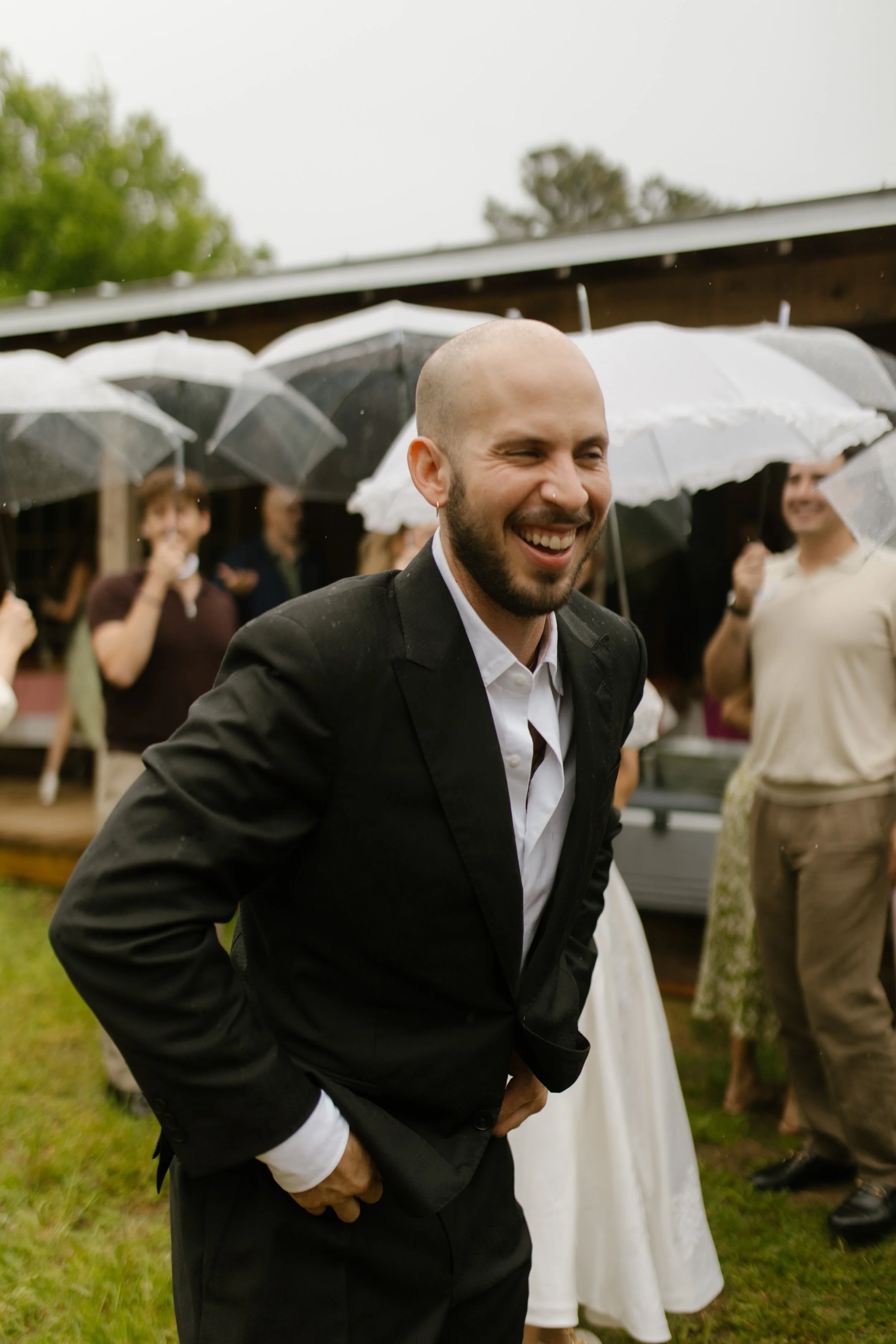 Groom laughing with wedding guests outside the venue during rehearsal dinner photography