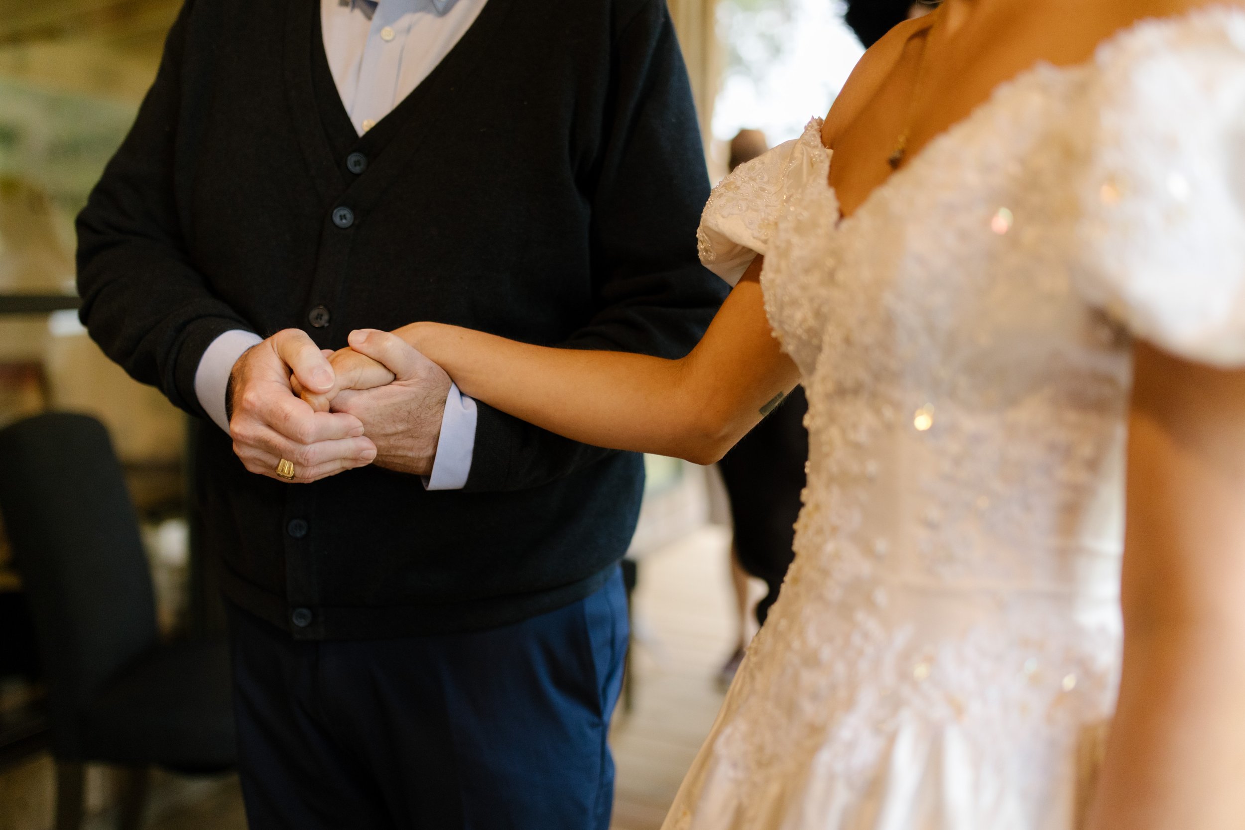 Bride holding hands with a family member during an emotional moment at the rehearsal dinner.