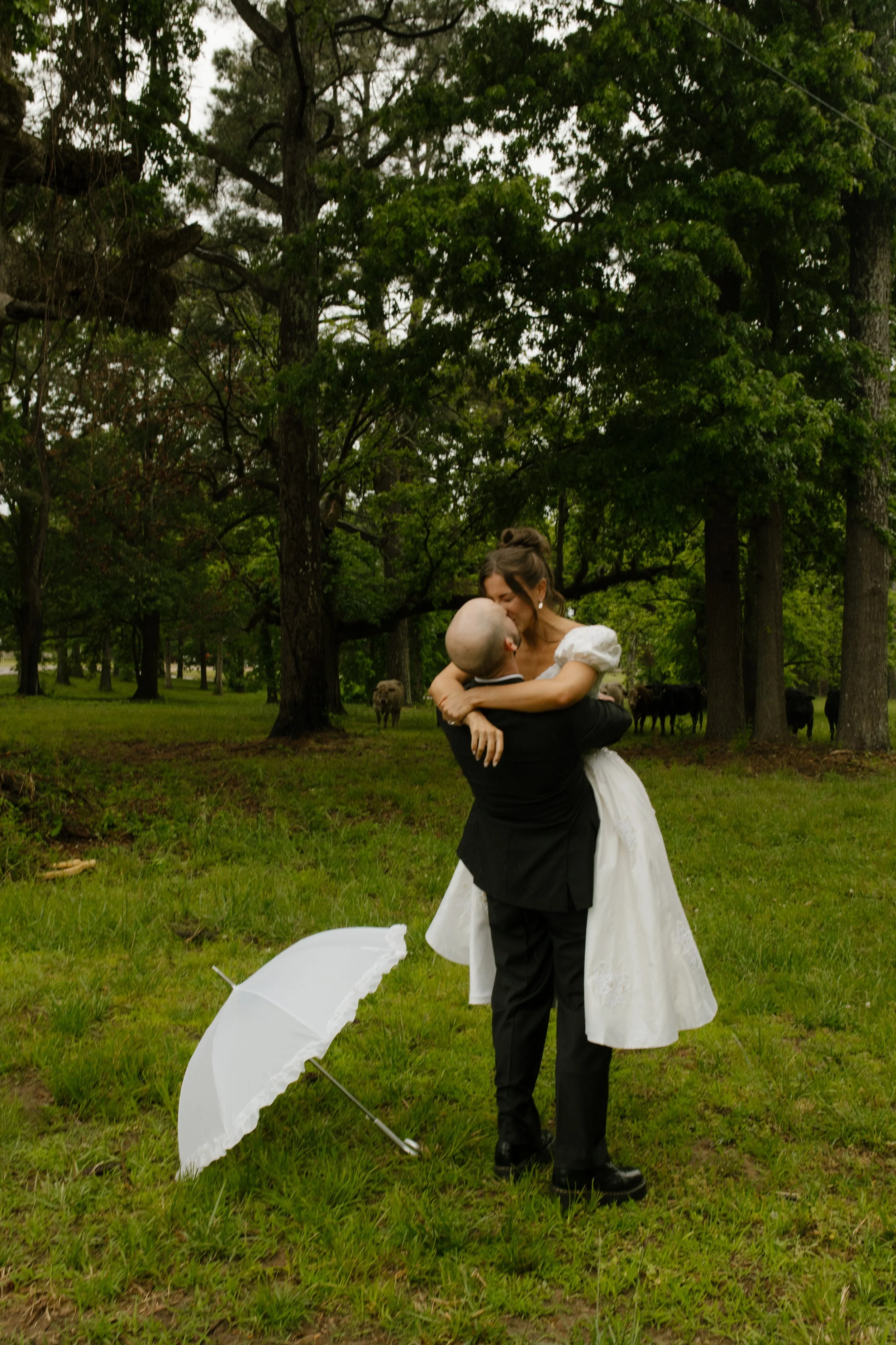 Groom lifting the bride in a grassy field during a romantic wedding rehearsal photography portrait session.