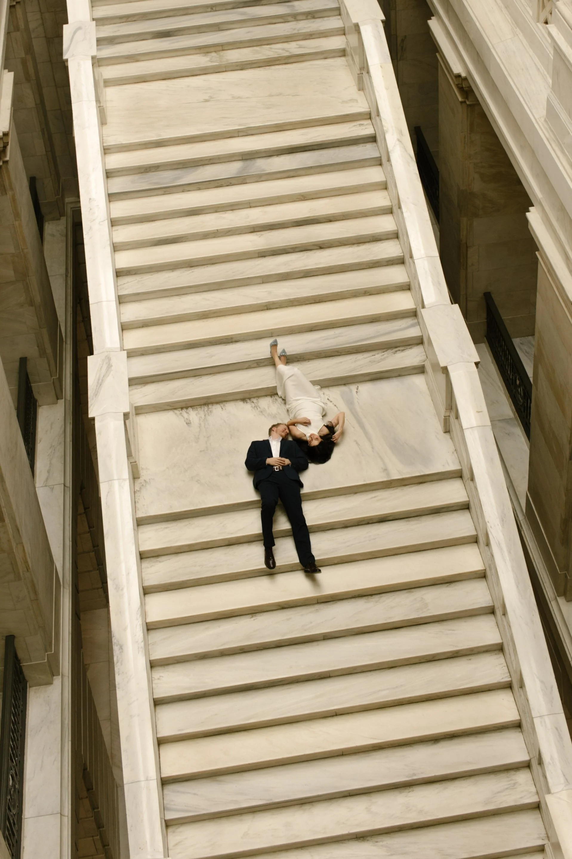 Overhead view of a couple lying together on the iconic marble staircase inside the Little Rock Courthouse