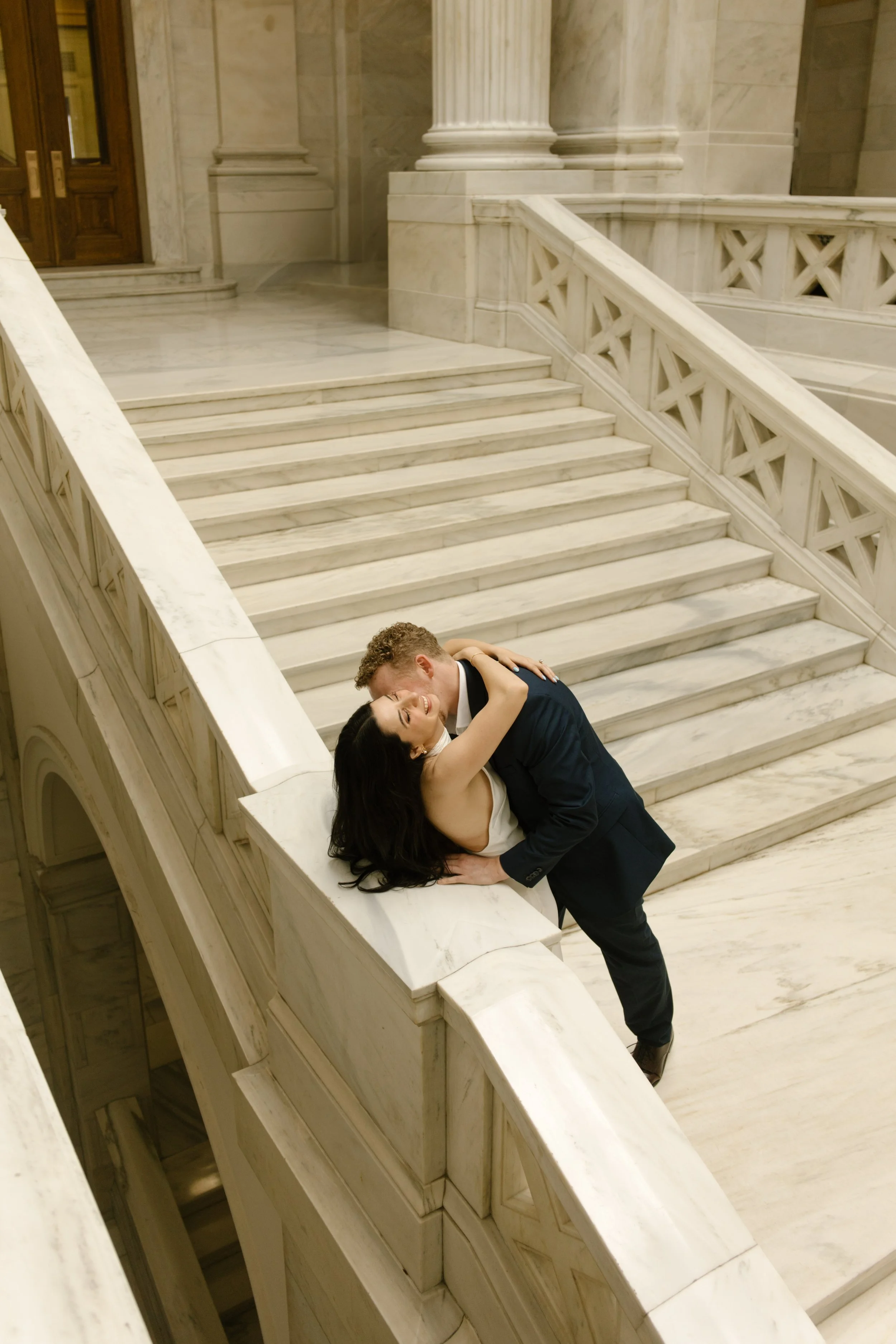 Editorial portrait of an engaged couple overlooking the marble atrium at the Little Rock Courthouse