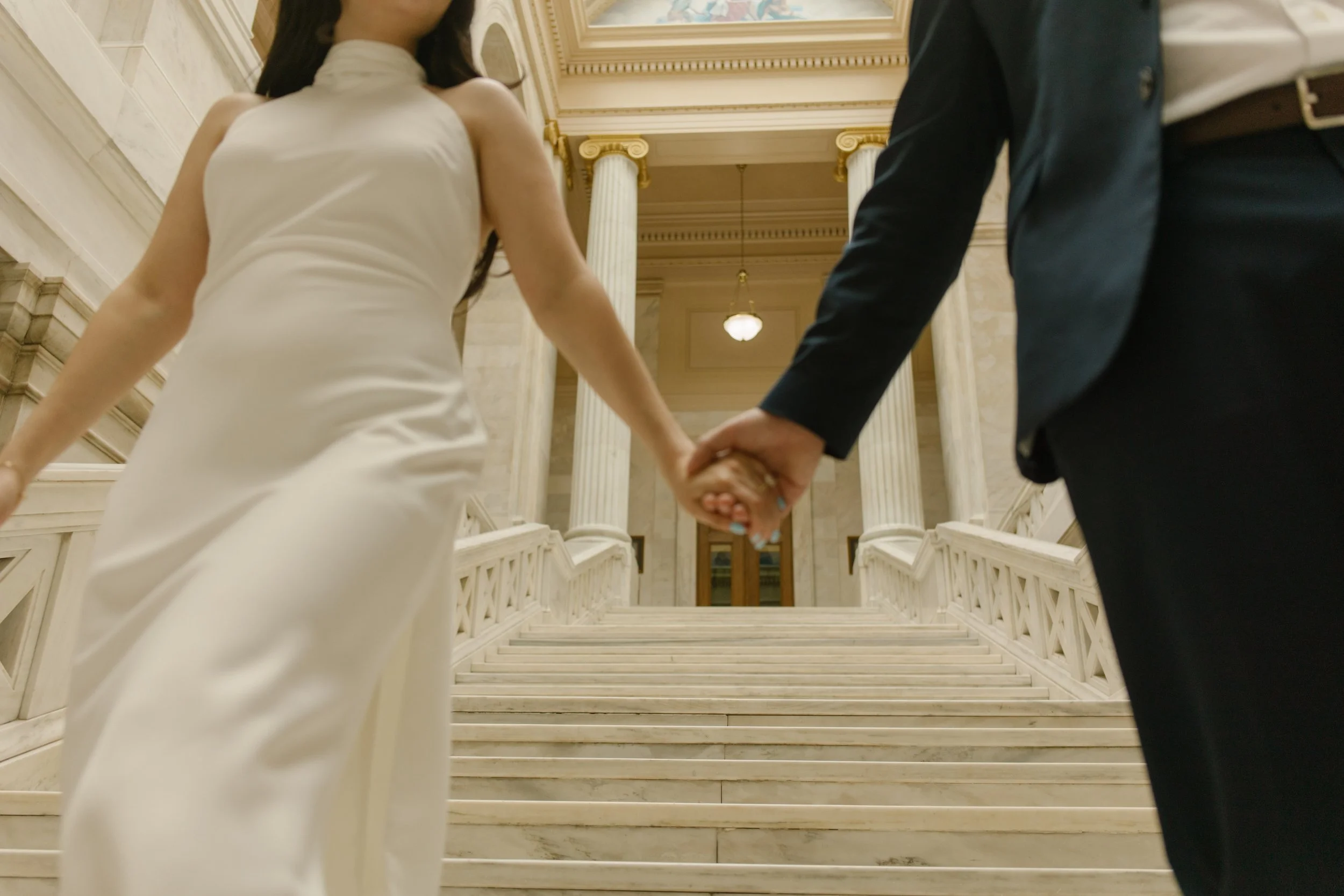 Couple holding hands while walking through the historic courthouse staircase