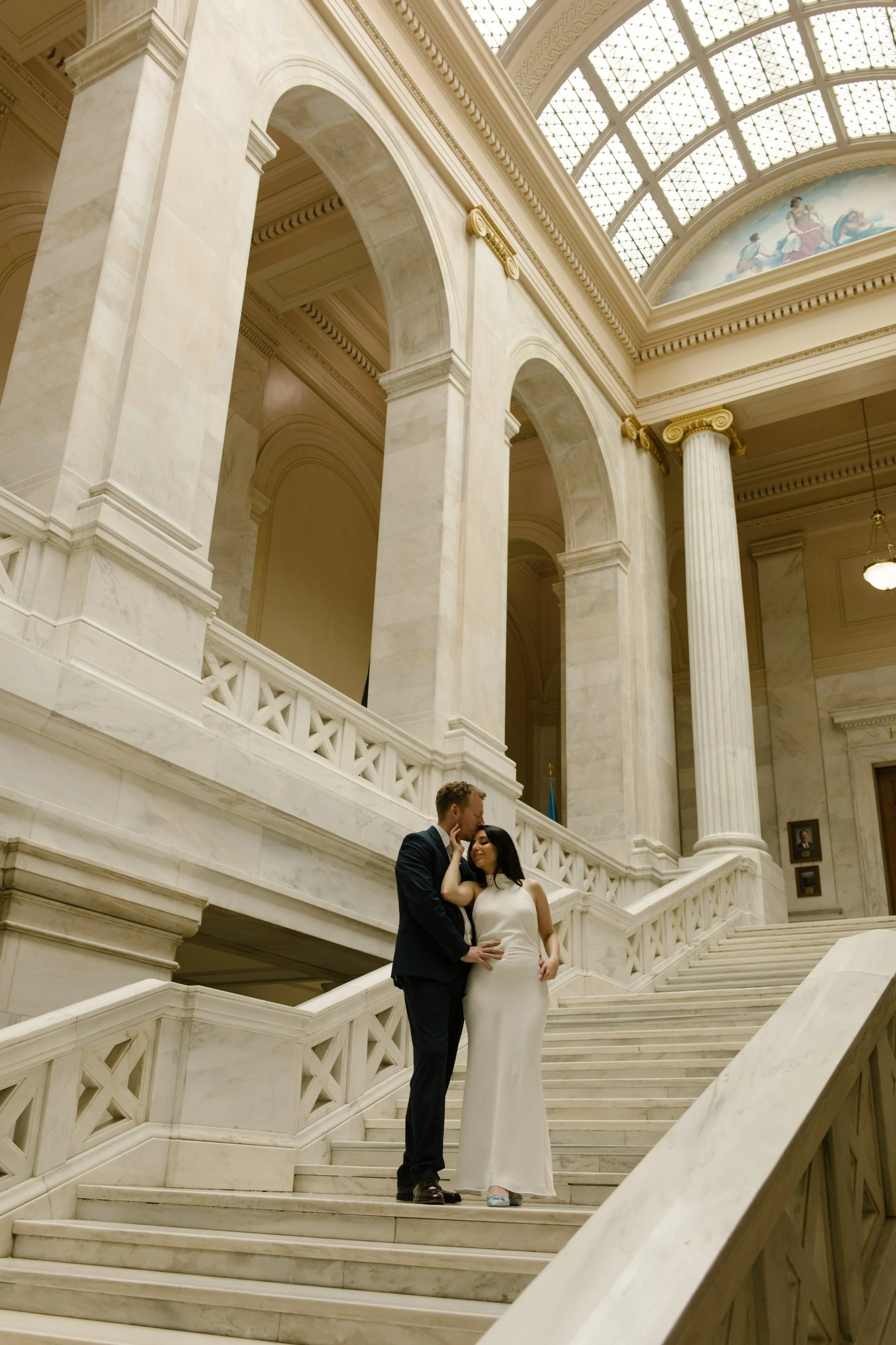 Couple embracing on the grand staircase inside the Little Rock Courthouse during an editorial engagement session