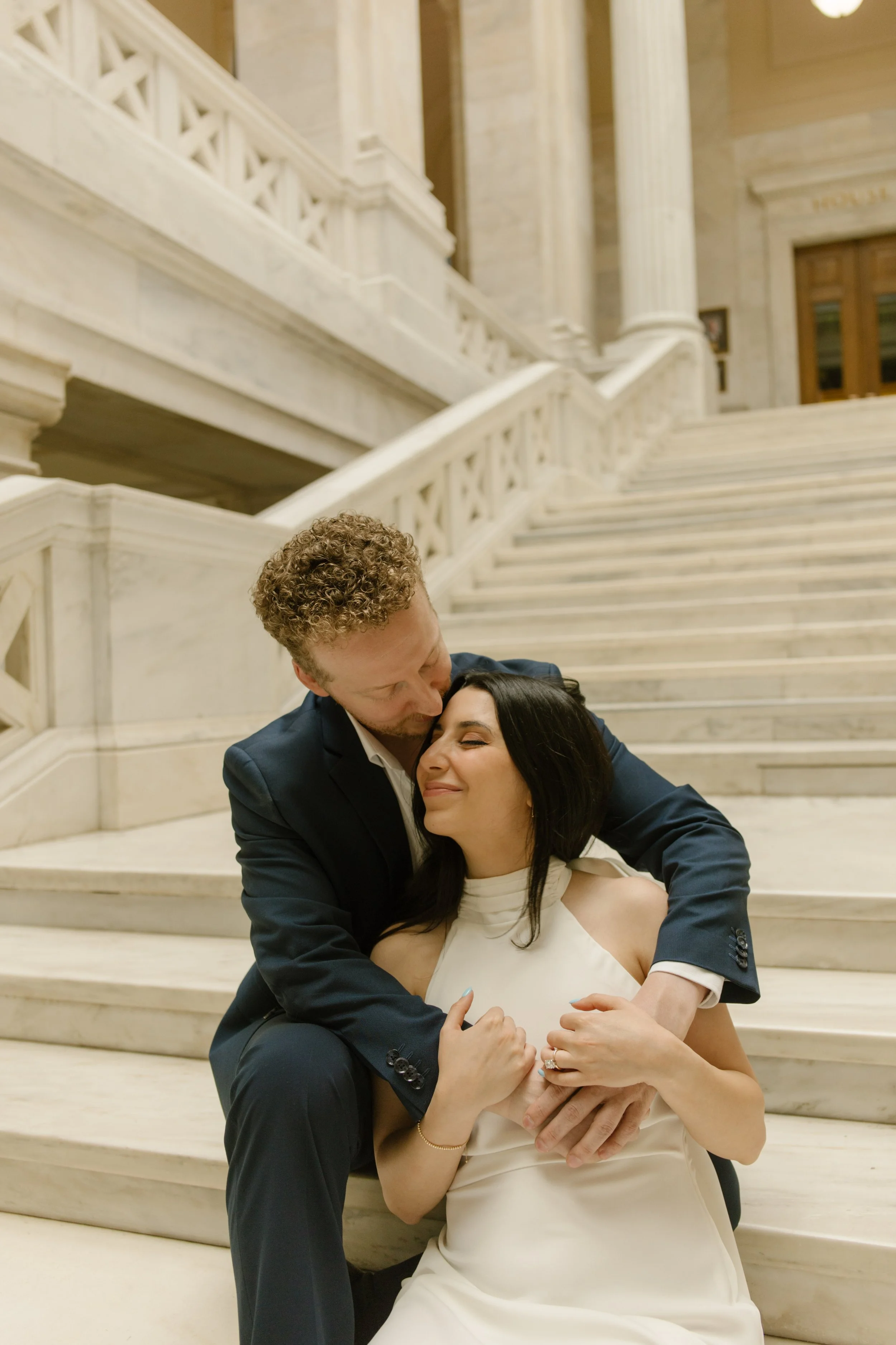 Bride and groom embrace on marble courthouse steps during an intimate portrait session.