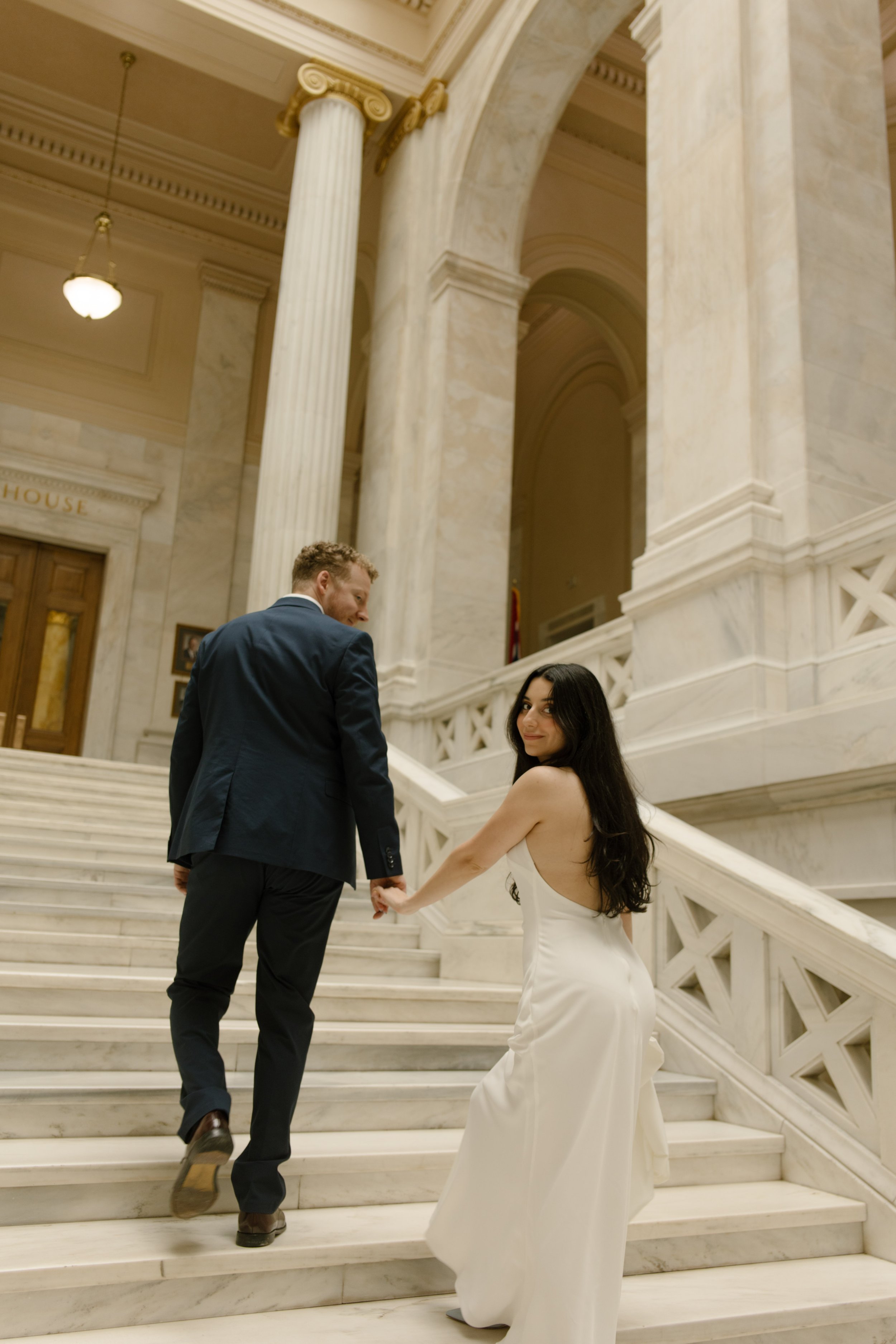 Couple looking back while climbing the historic marble stairs inside the courthouse
