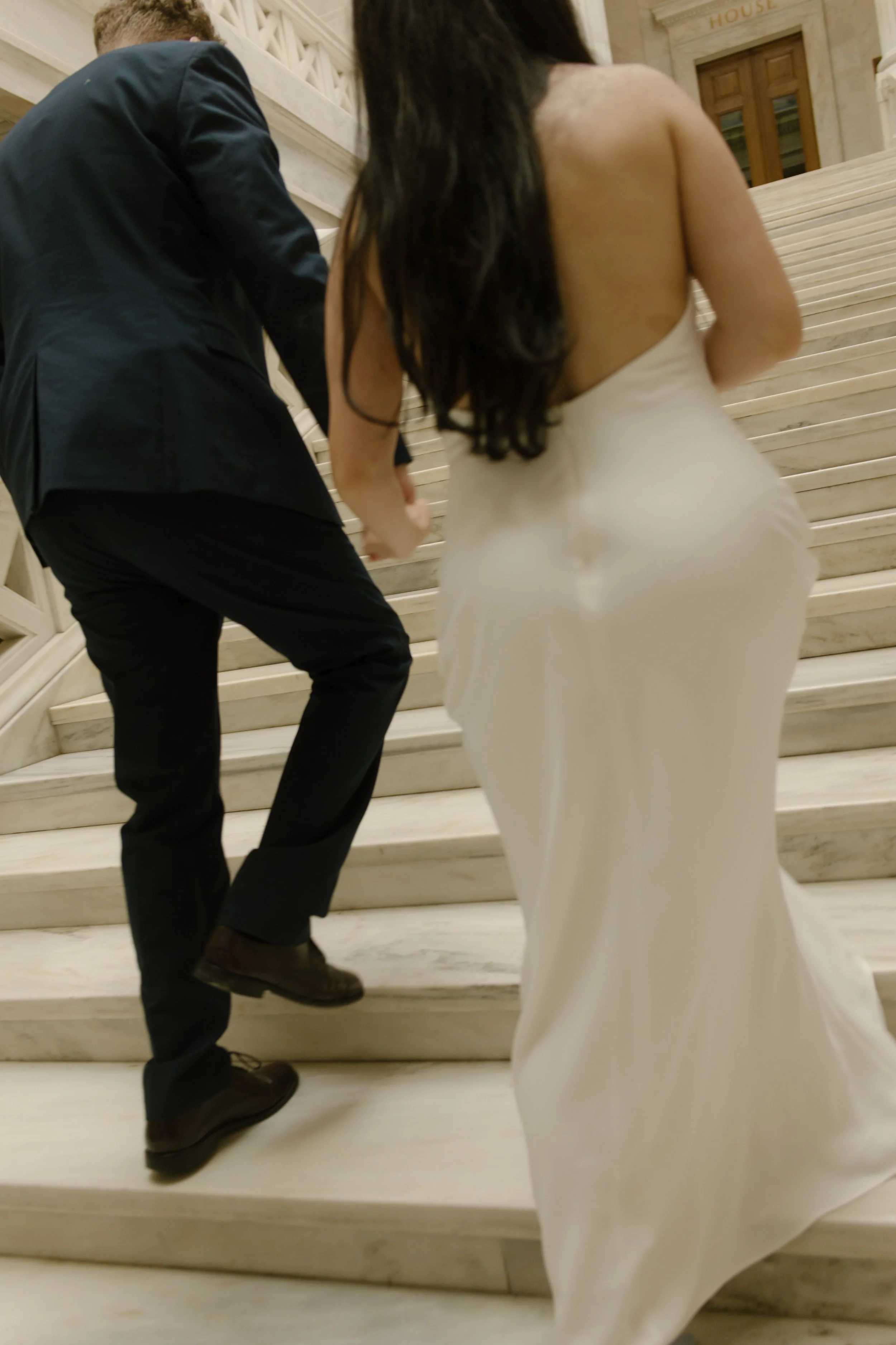 Bride and groom walking hand in hand up the grand staircase during a Little Rock Courthouse engagement session