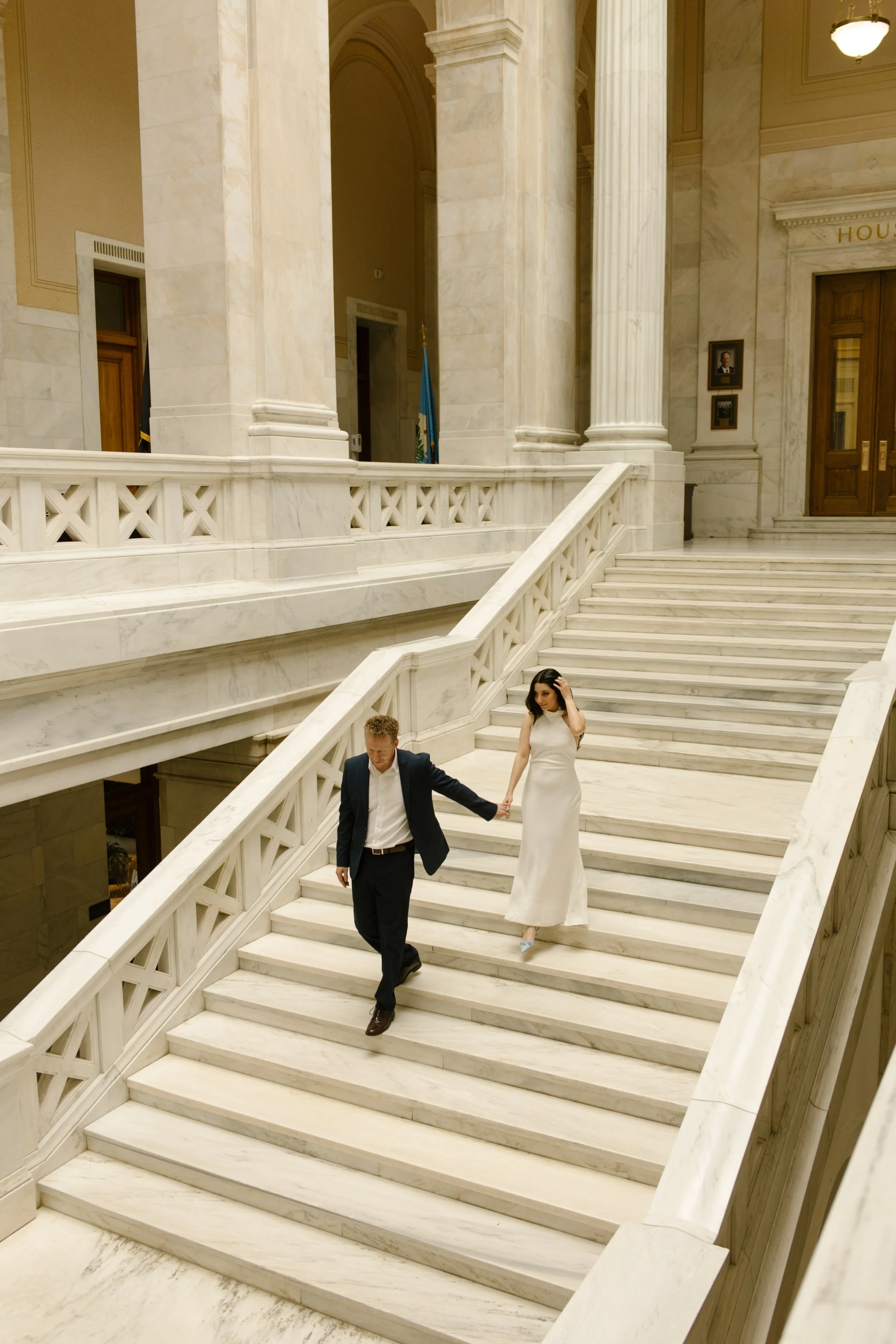 Editorial portrait of a couple descending the elegant staircase at the Little Rock Courthouse