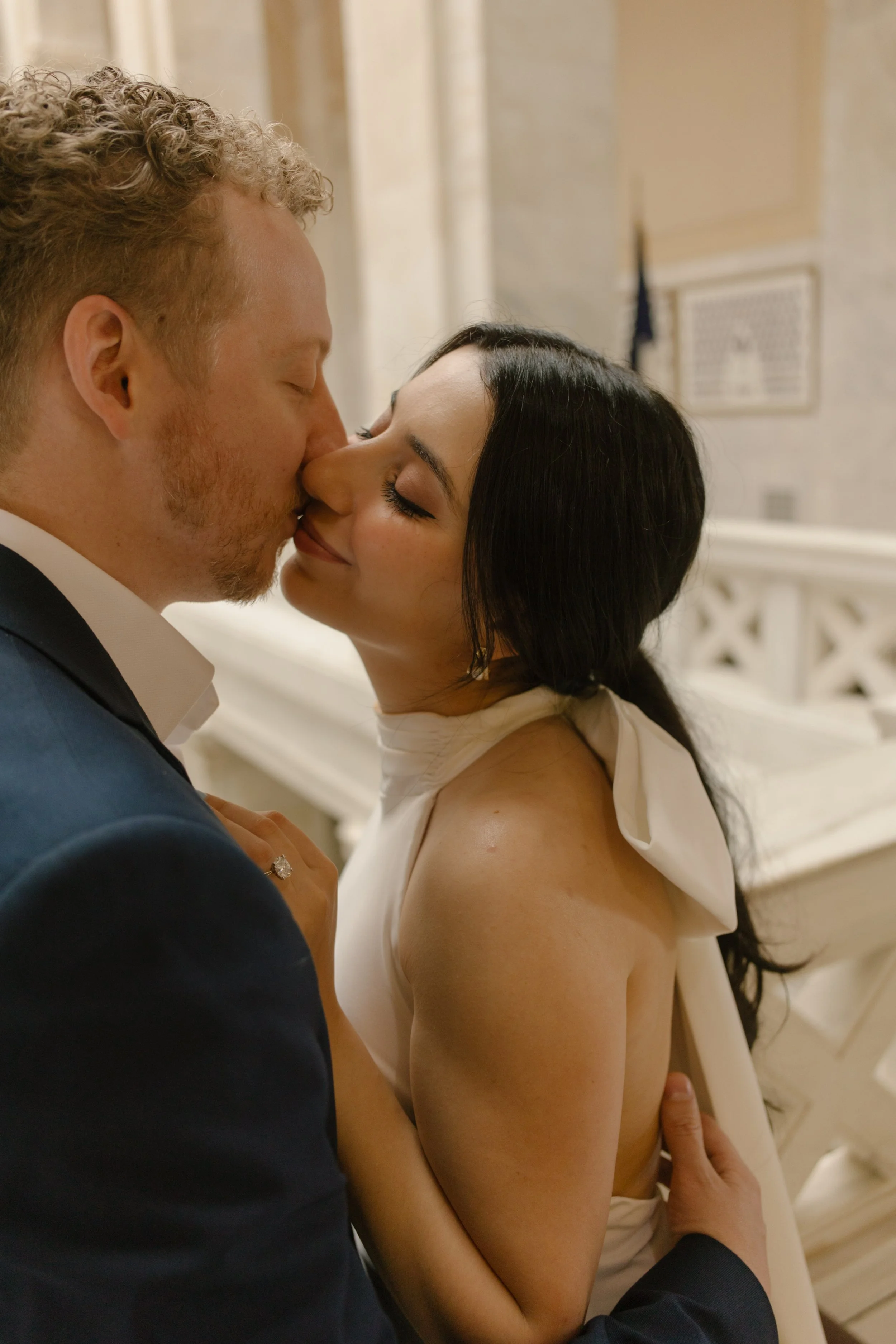 Close-up of an engaged couple sharing a kiss beneath the marble architecture of the Little Rock Courthouse