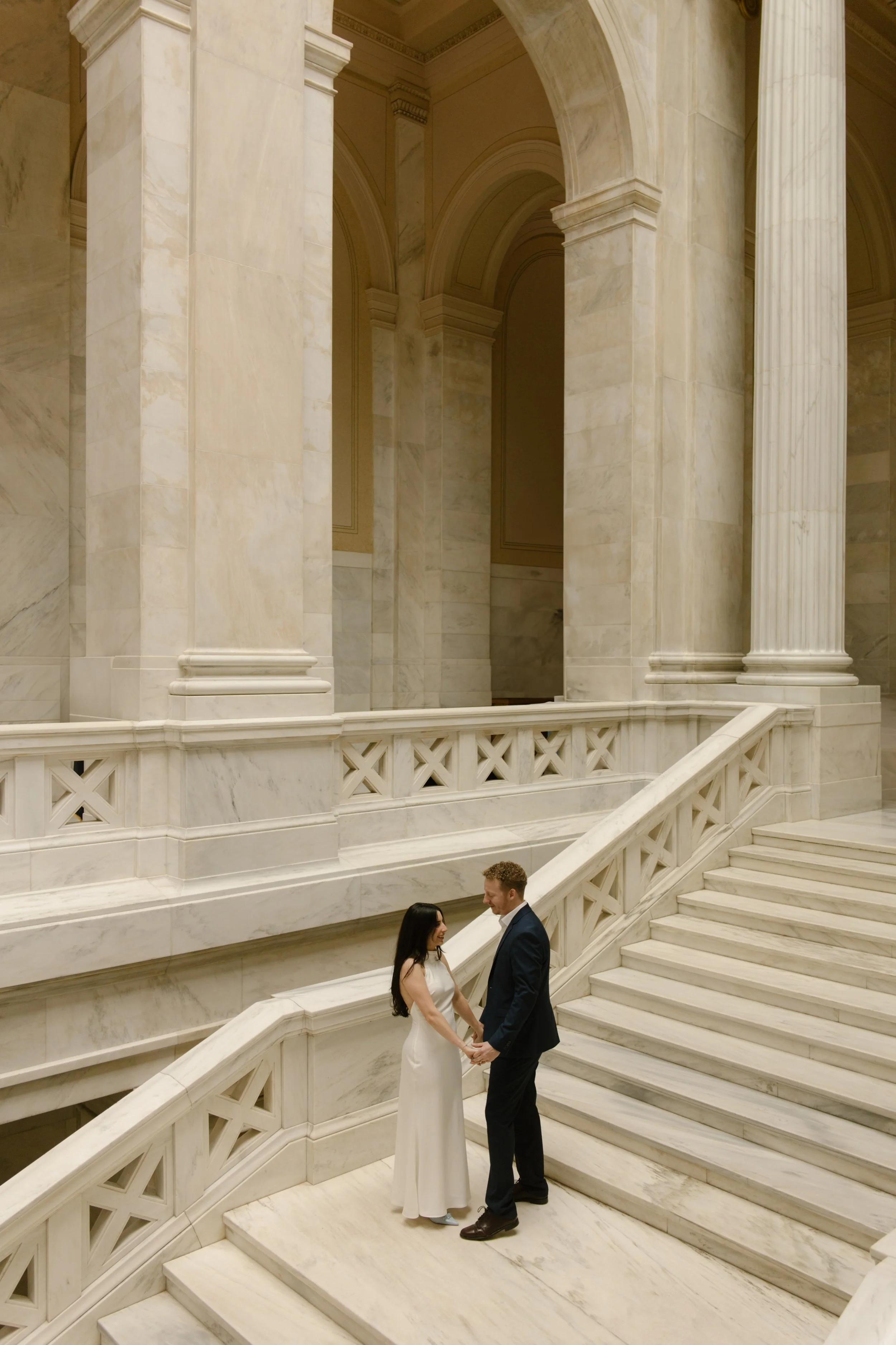 Couple holding hands on the marble landing during a Little Rock Courthouse engagement session