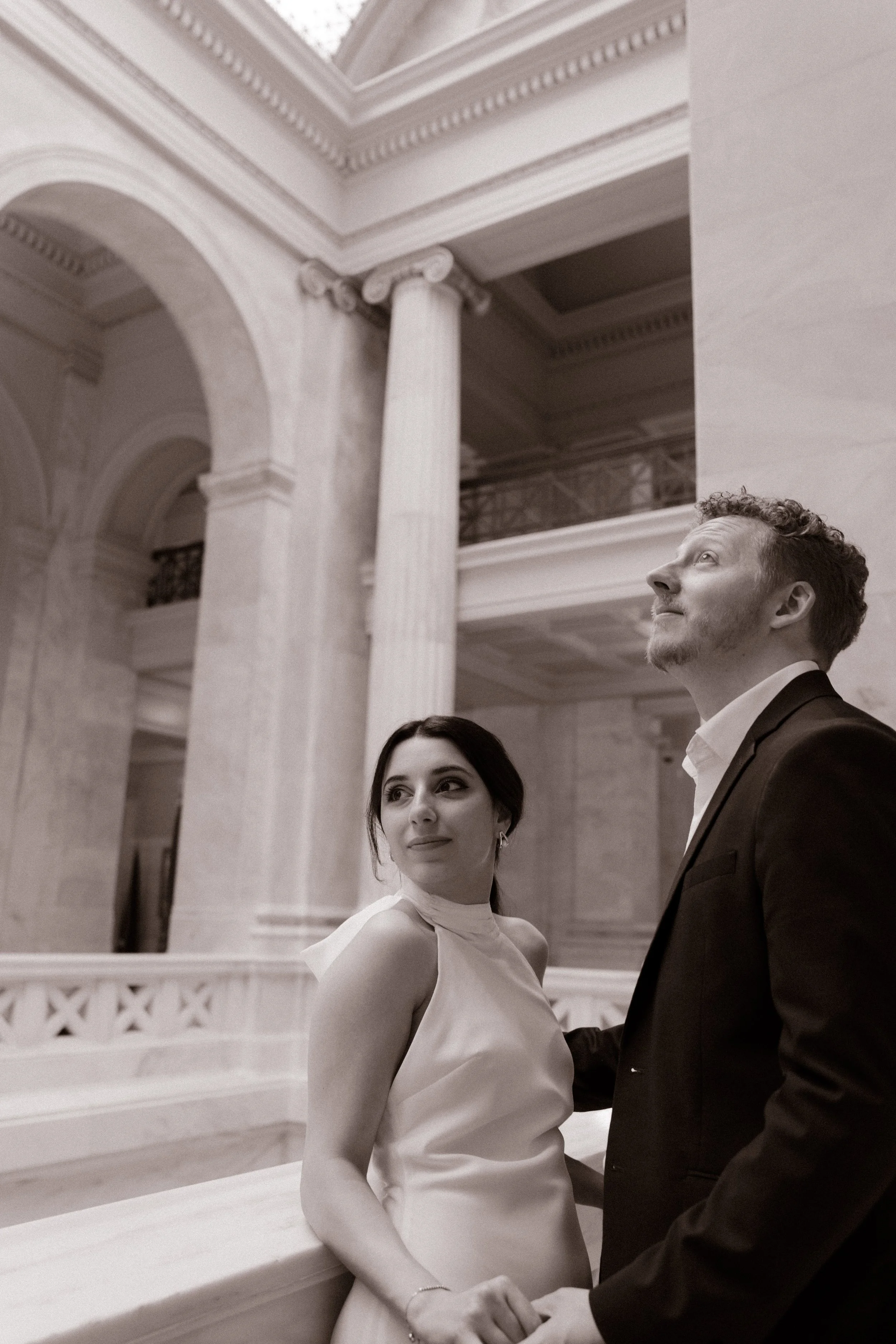 Black and white portrait of an engaged couple surrounded by the timeless architecture of the Little Rock Courthouse