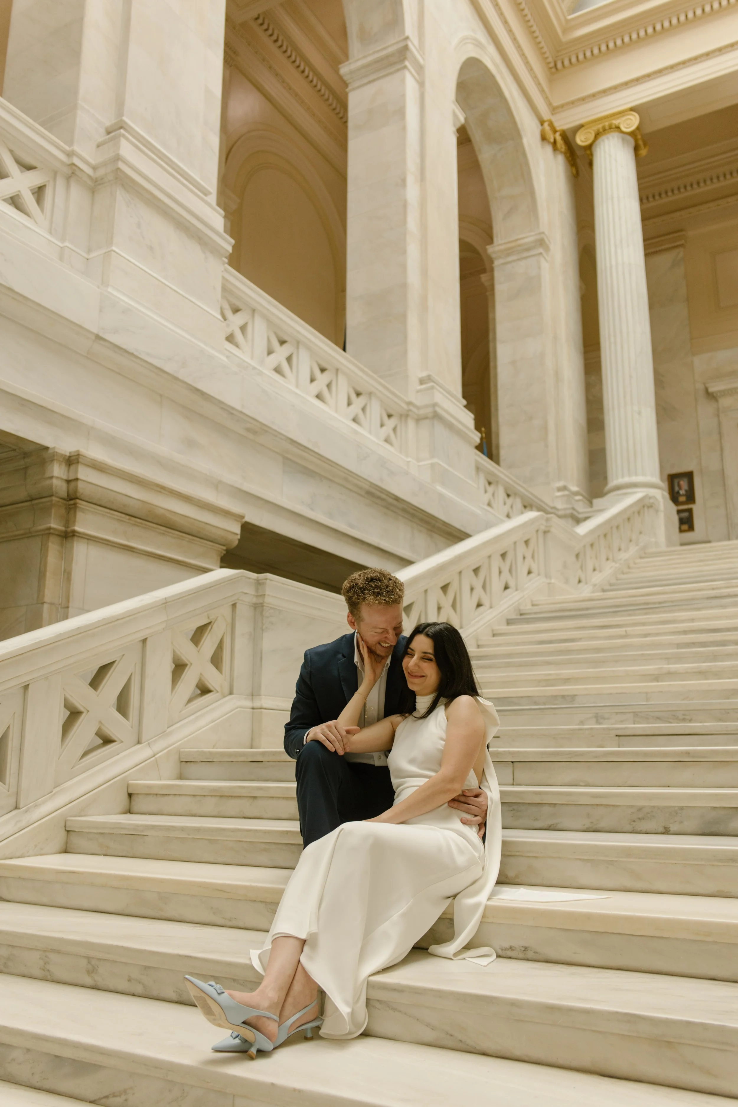 Candid engagement photo of a couple laughing together on the courthouse steps